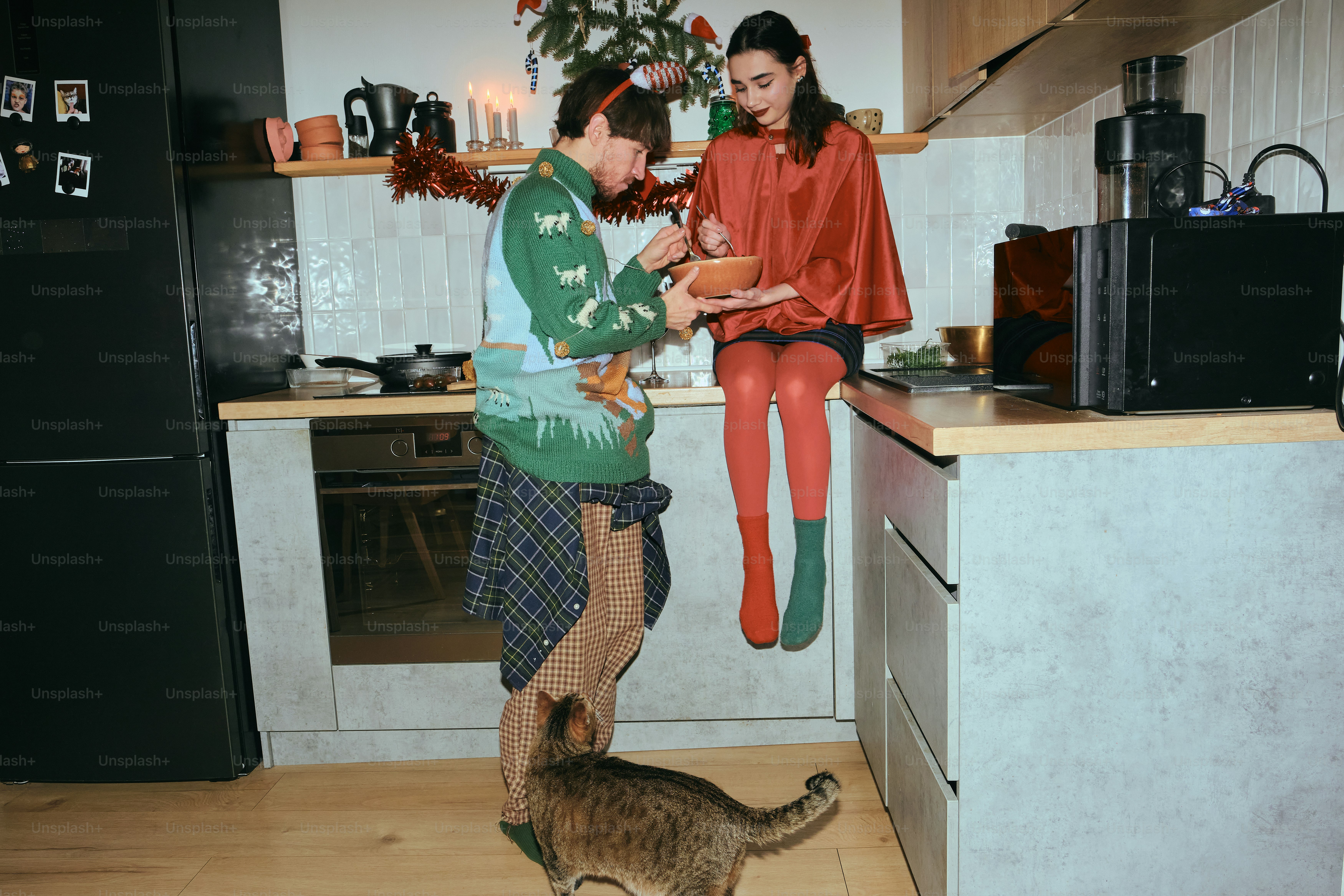 Coppia in abiti festivi in cucina con un gatto.