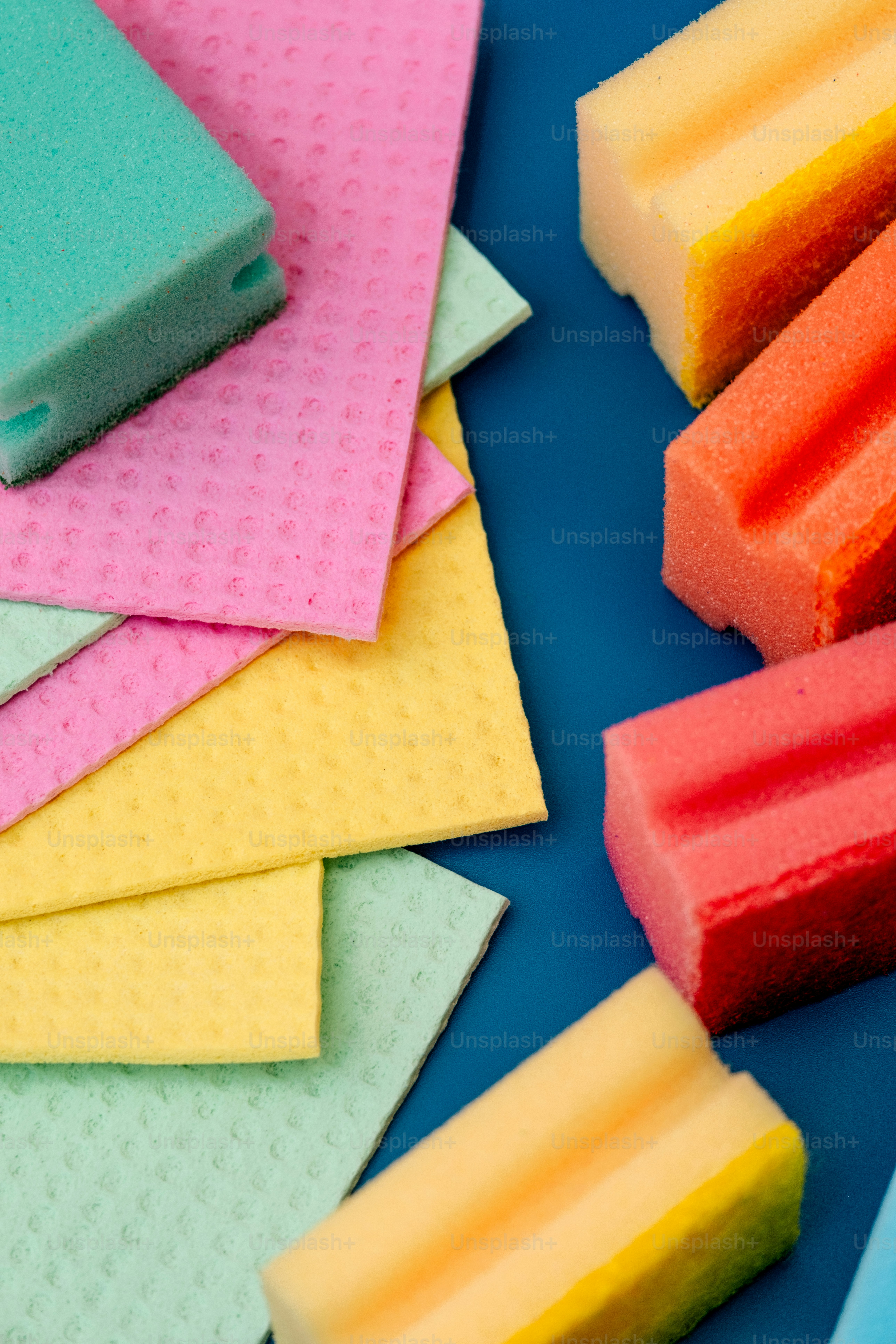 Colorful sponges and cloths arranged on a blue surface.