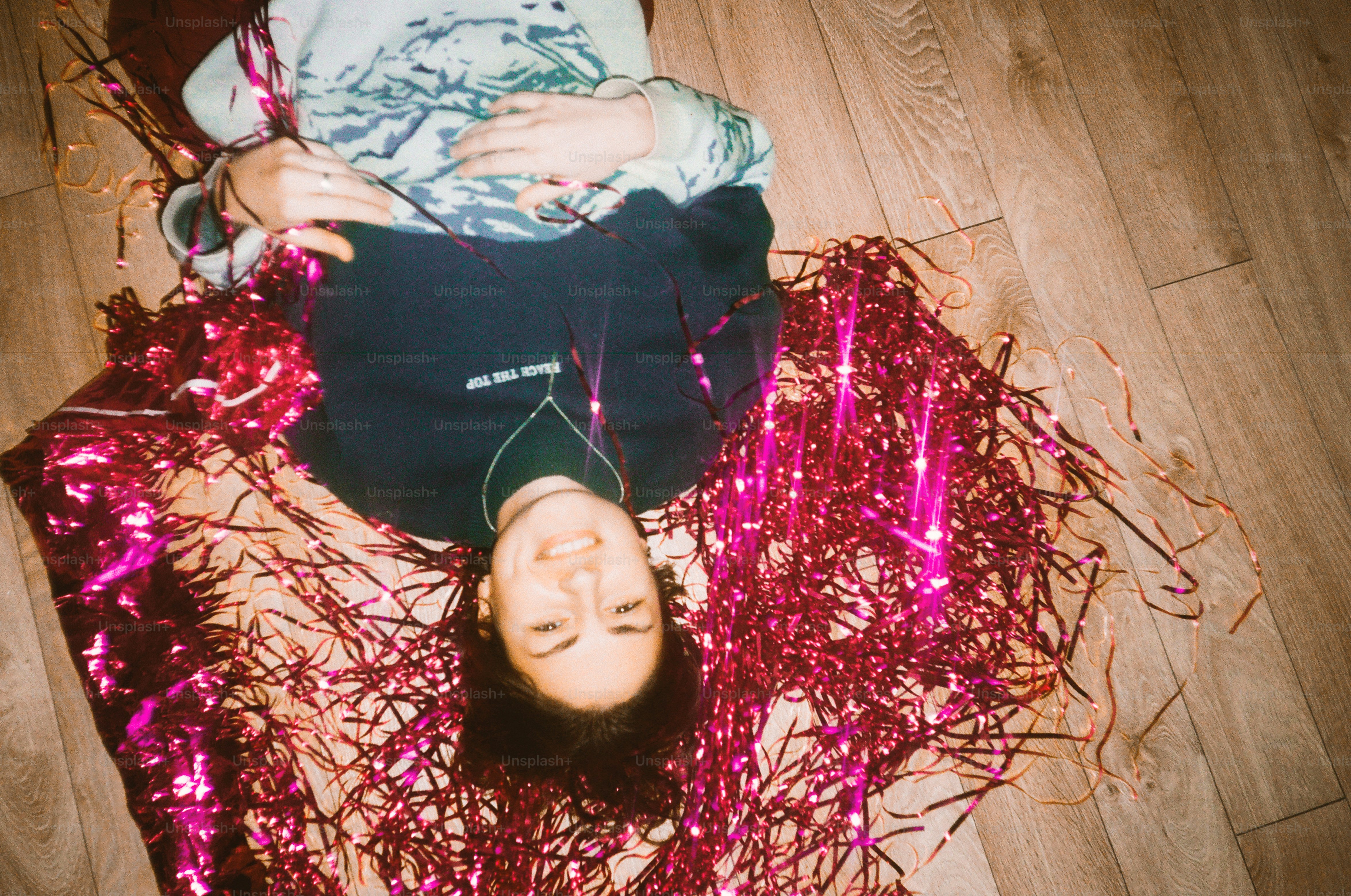 Young person lying on shiny pink tinsel on floor