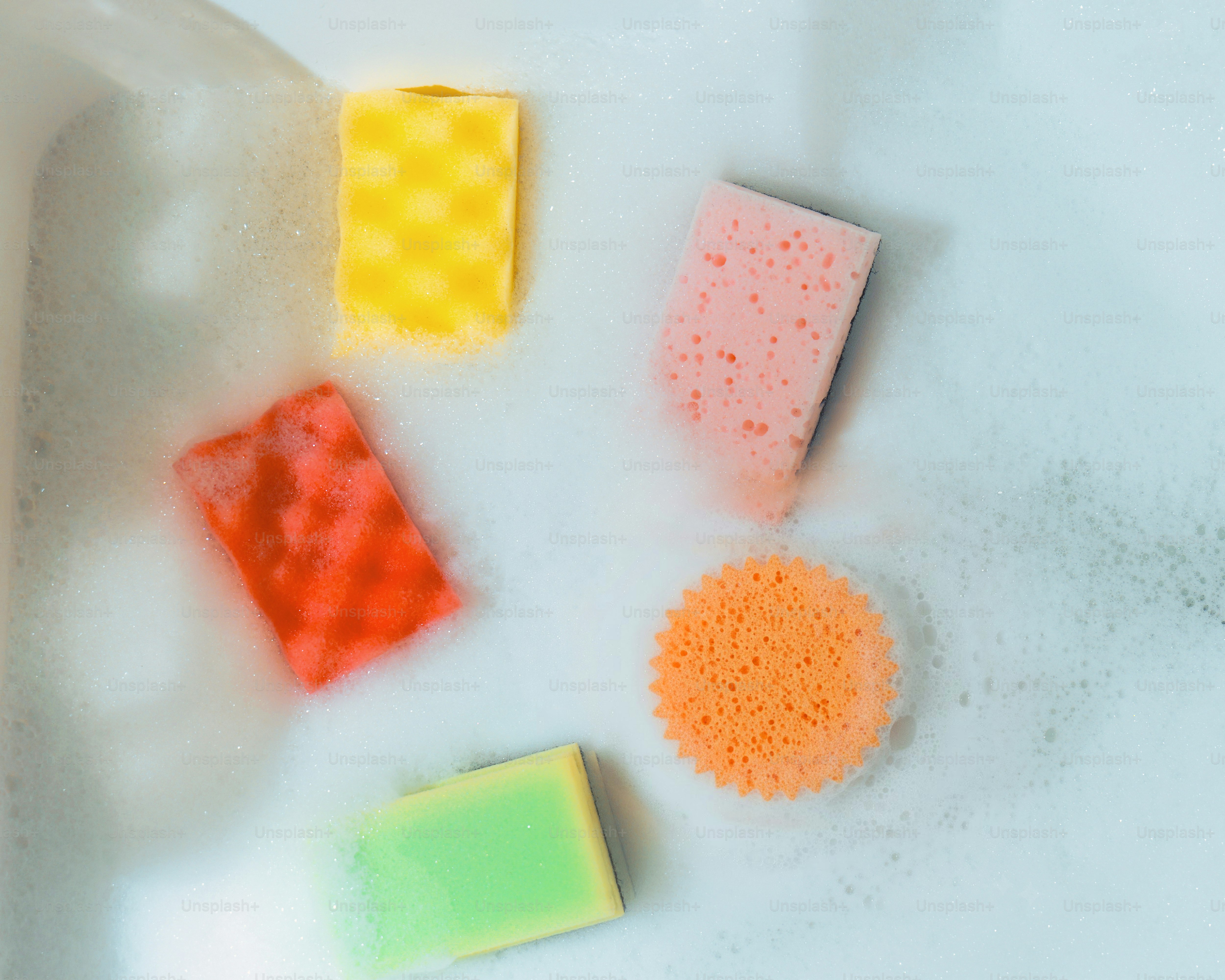 Colorful sponges floating in soapy water