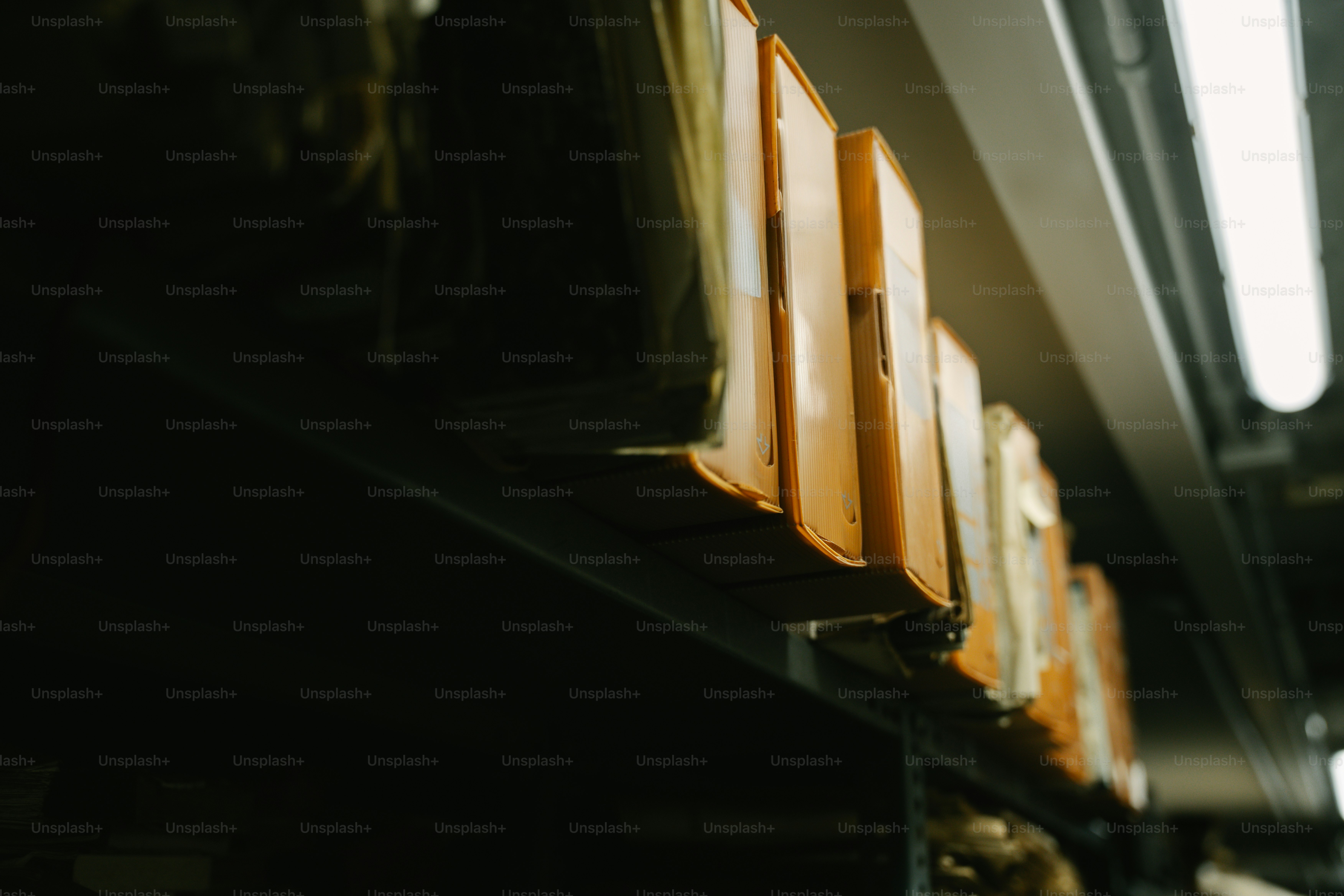 Orange binders on a shelf in a dark room.