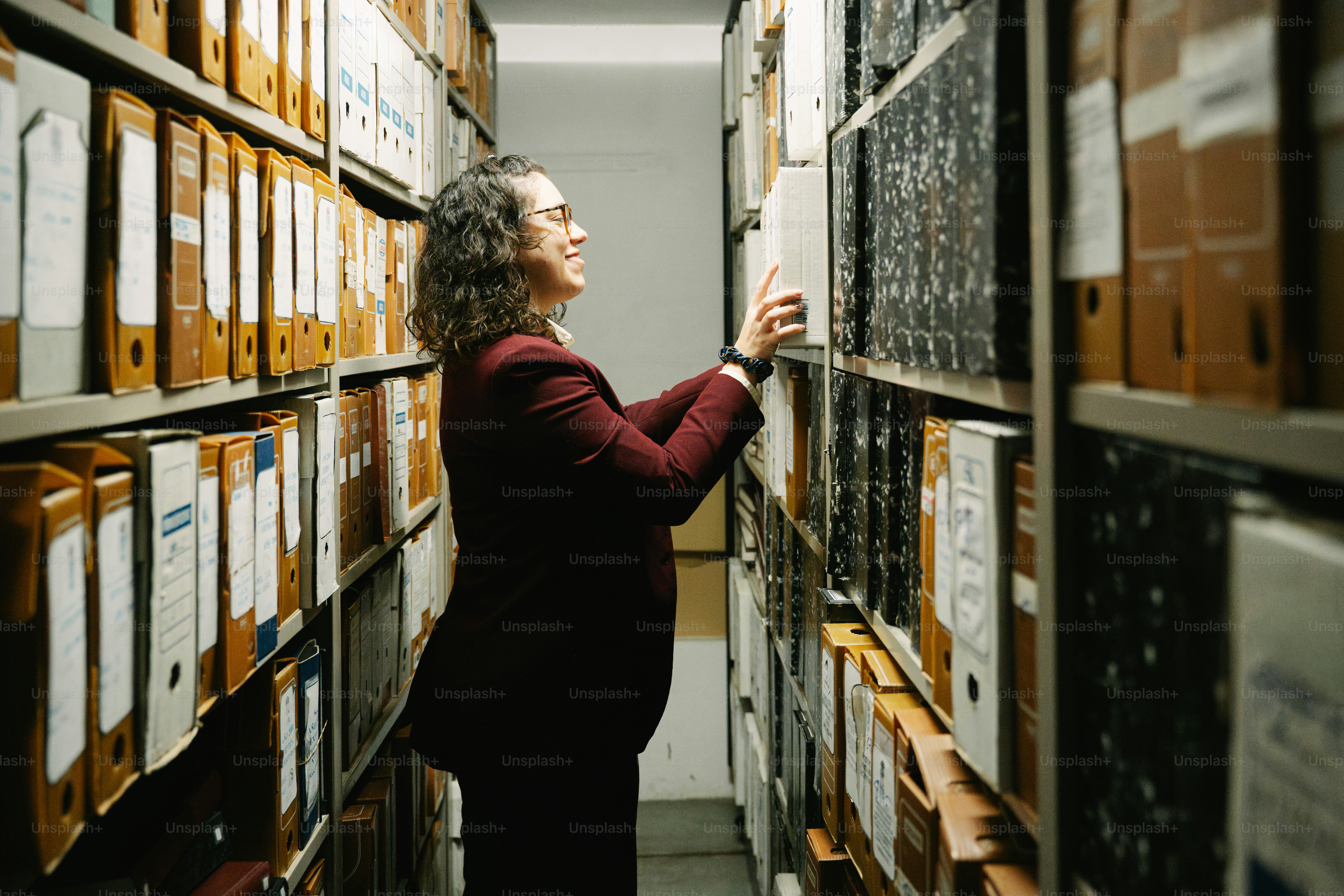 Archivist organizing files in a large archive room.