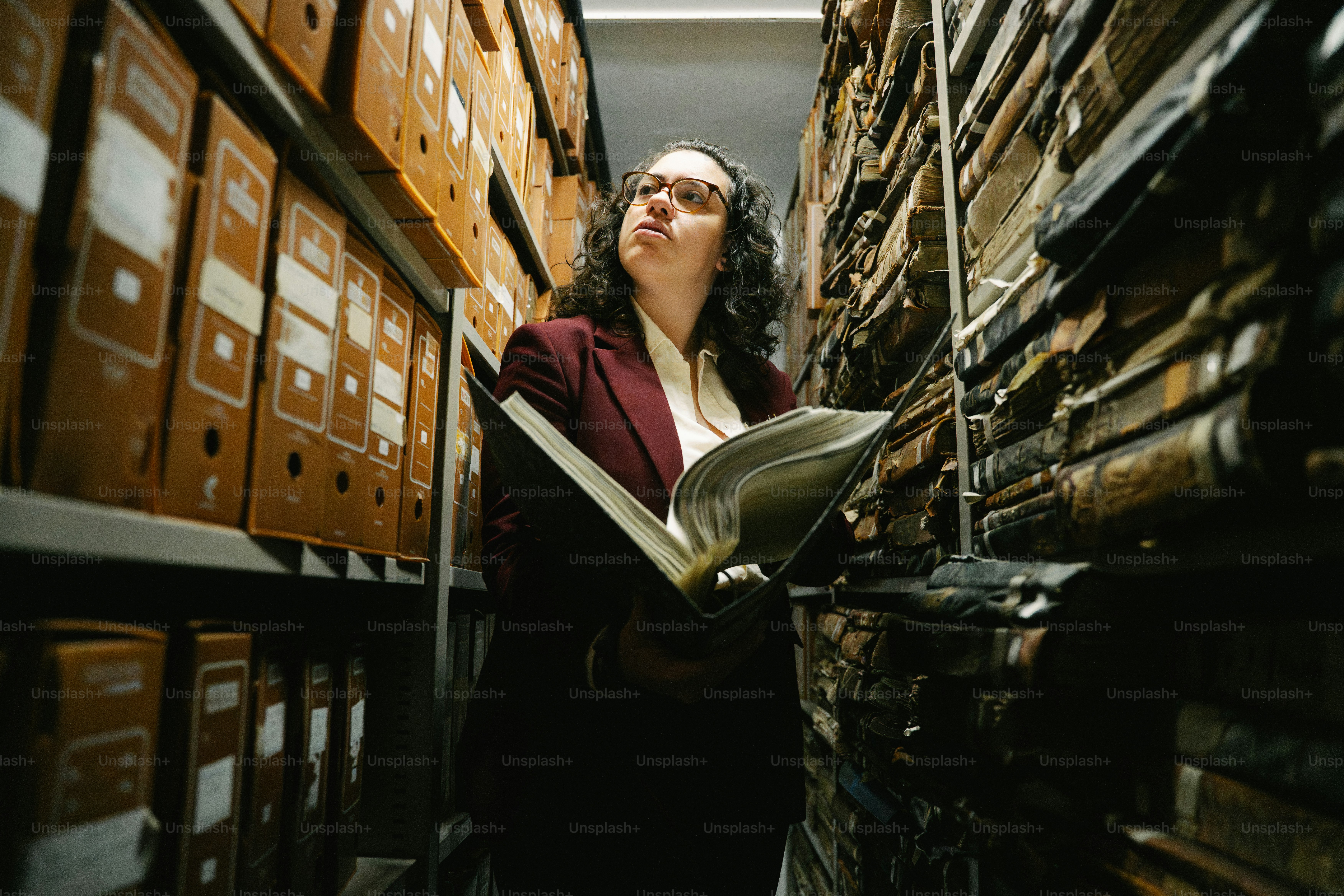 Archivist examining old books in a library archive.