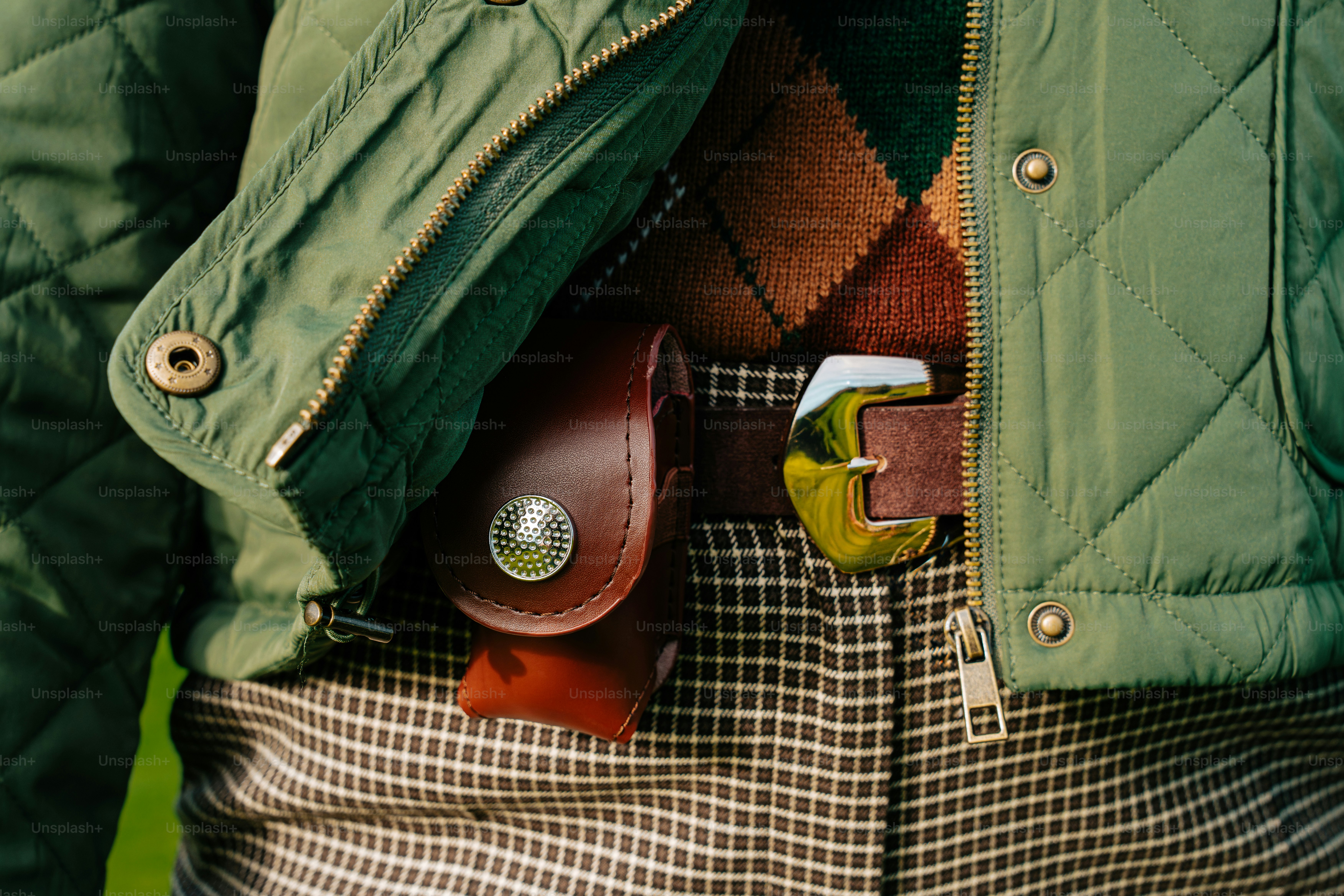 Persona que lleva chaqueta acolchonada, jersey de argyle y pantalones de cuadros.