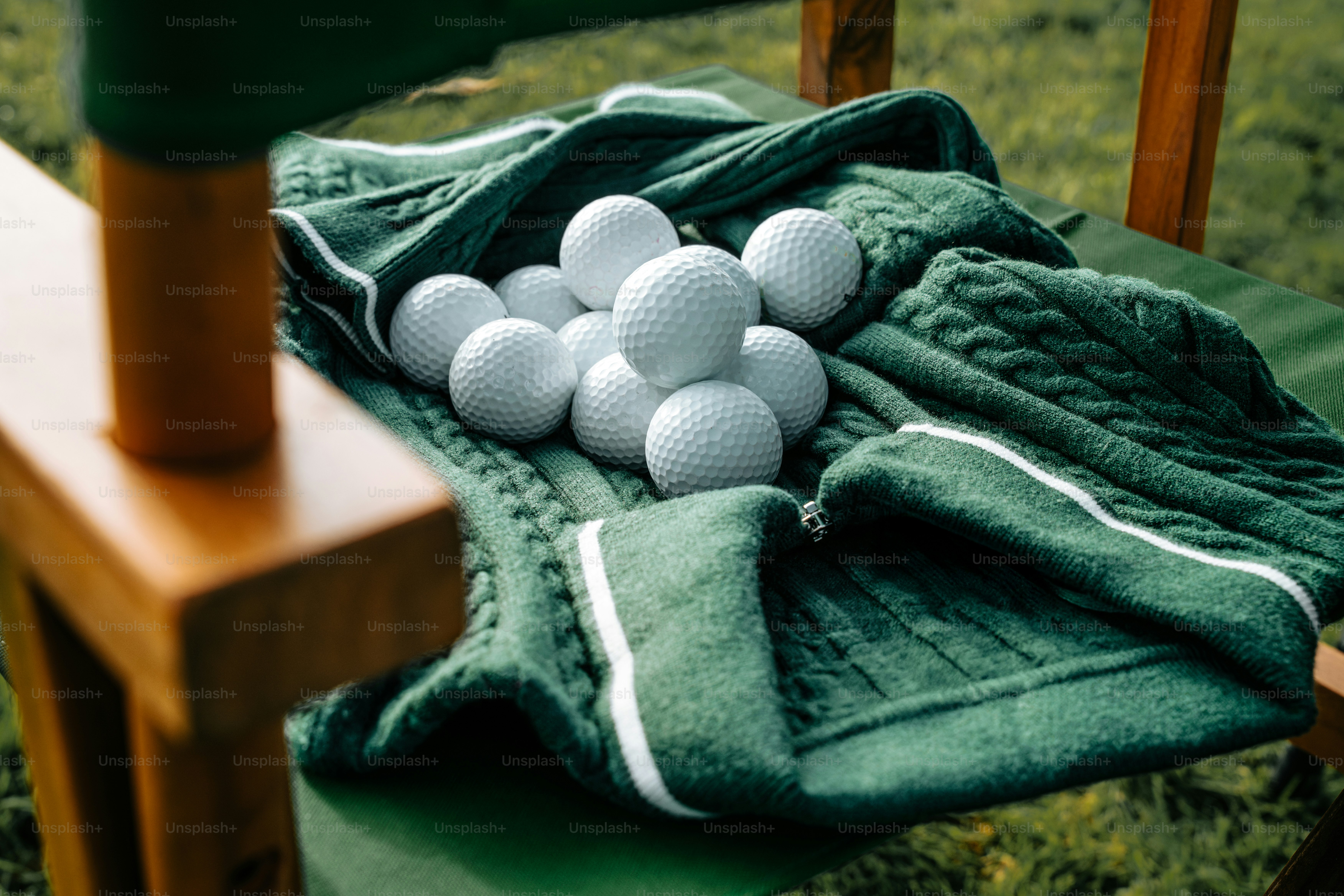 Golf balls piled on a green towel on a chair