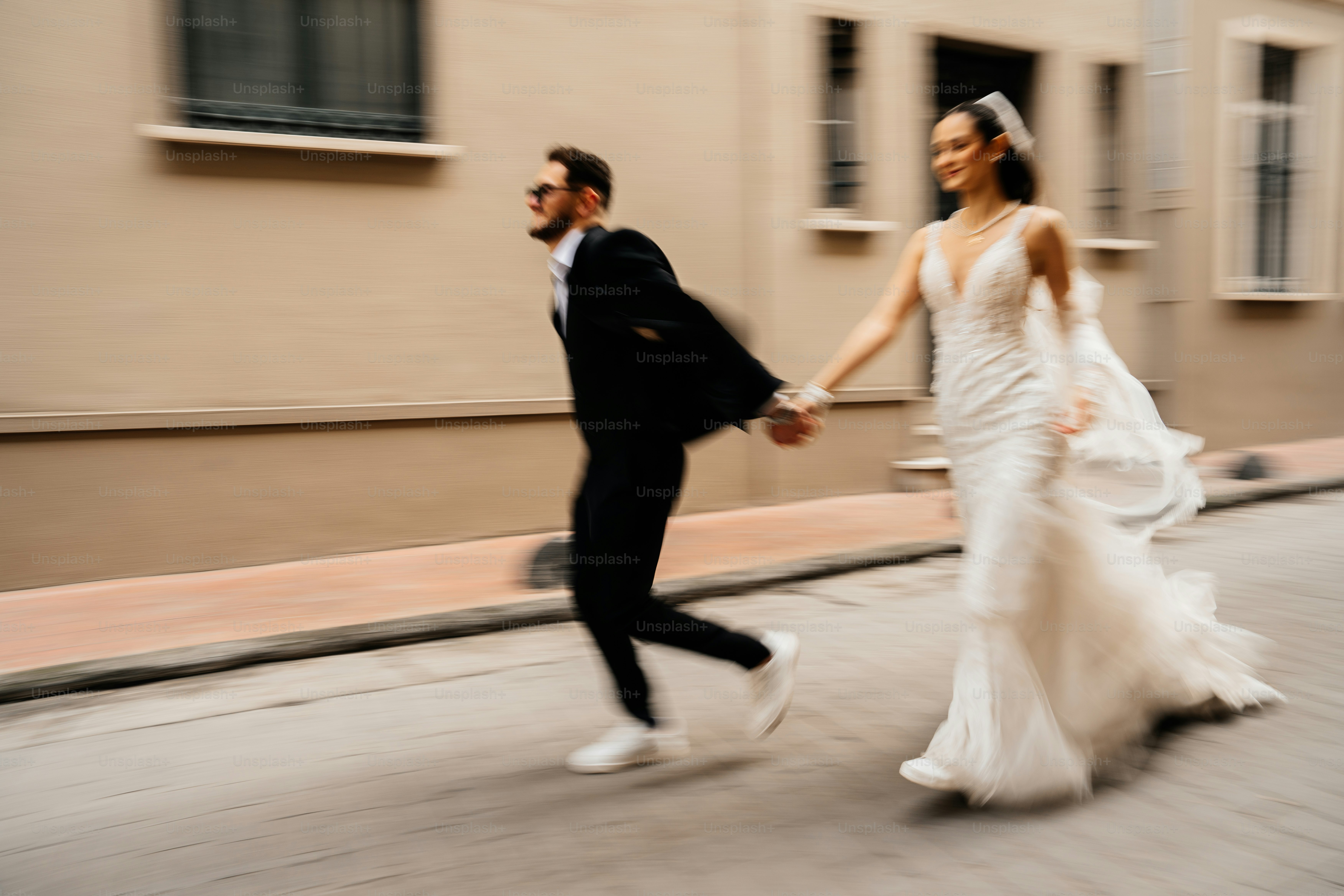 Bride and groom running hand in hand on street