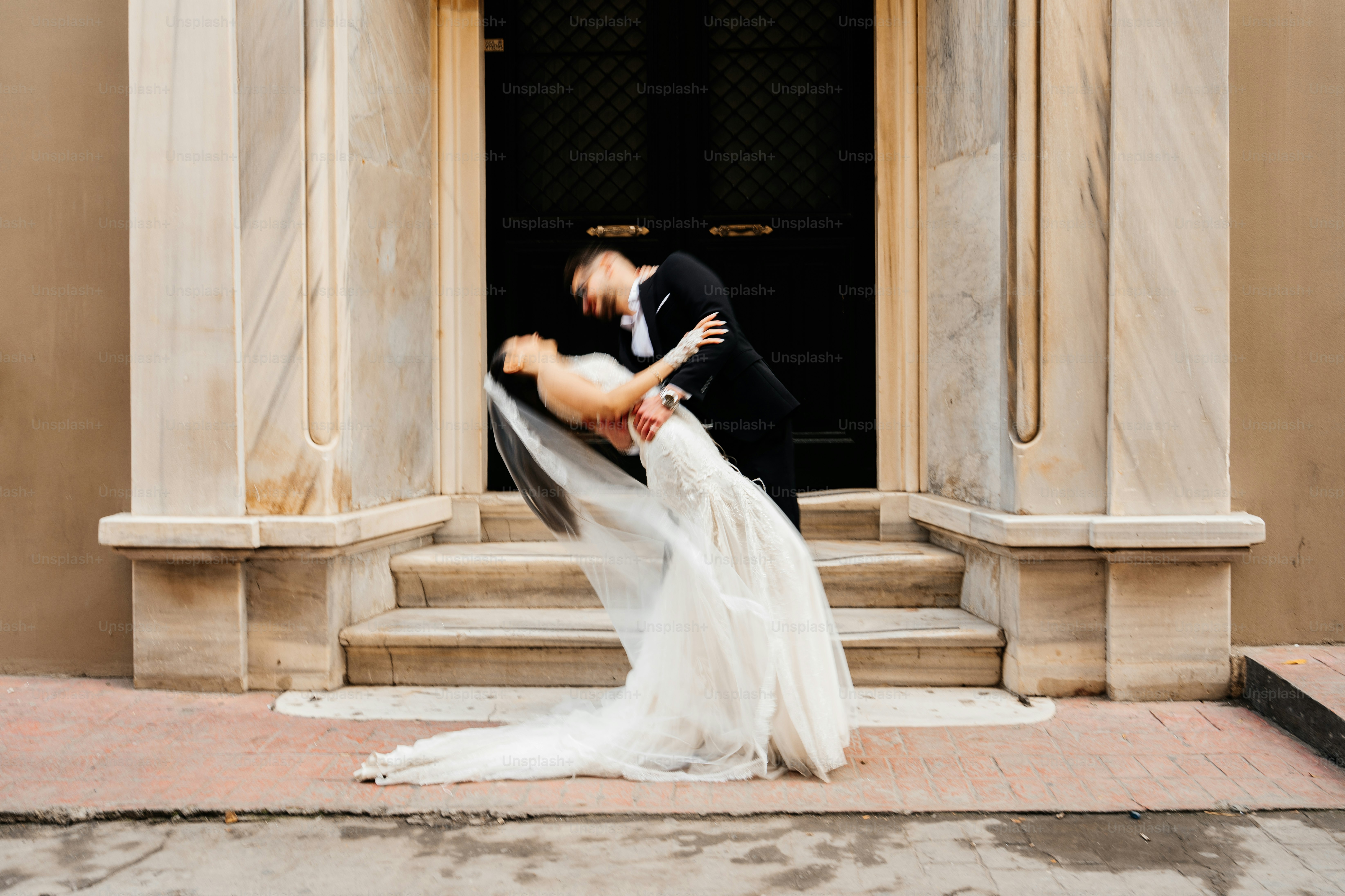 Groom dips bride in front of grand entrance