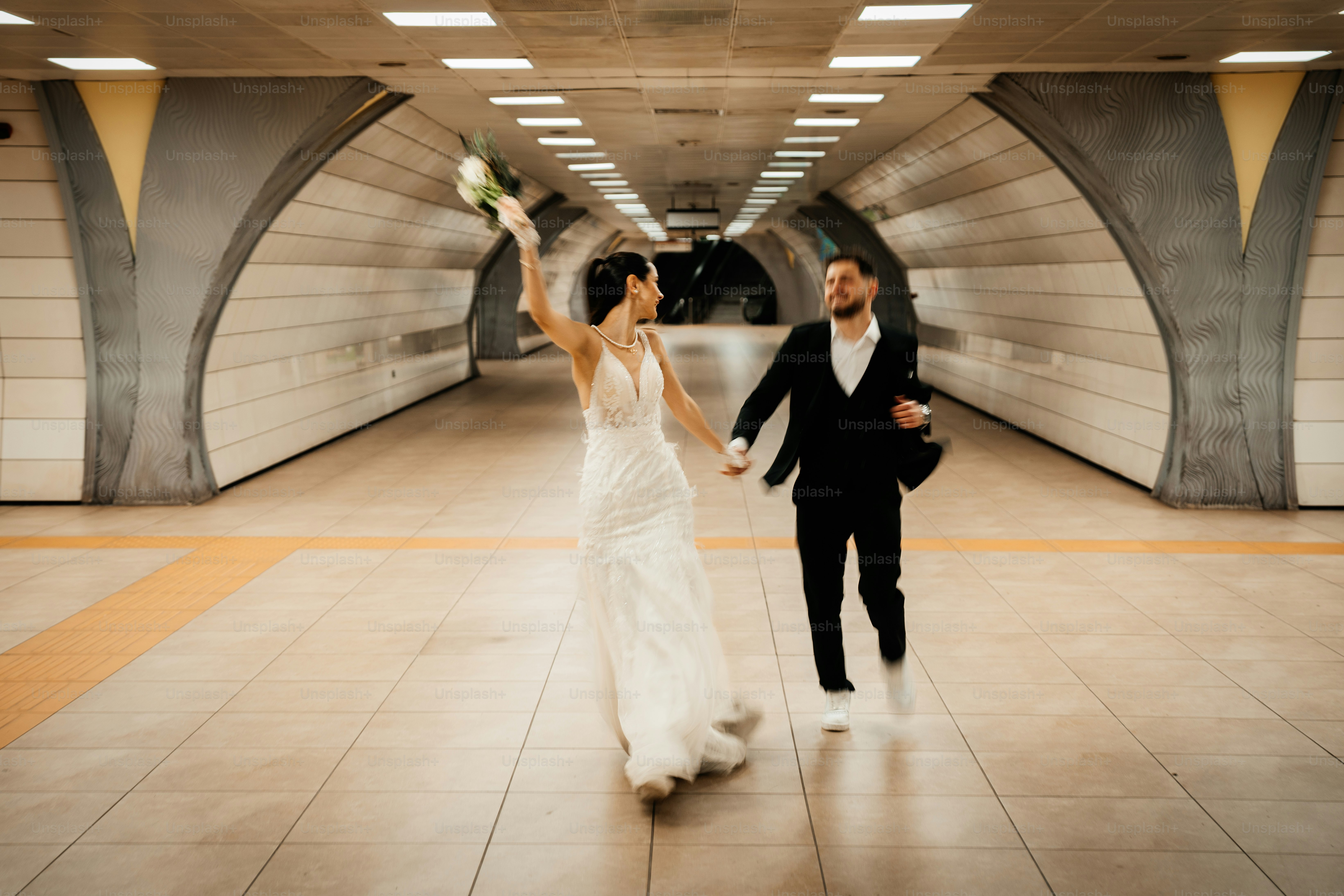 Bride and groom running in subway tunnel