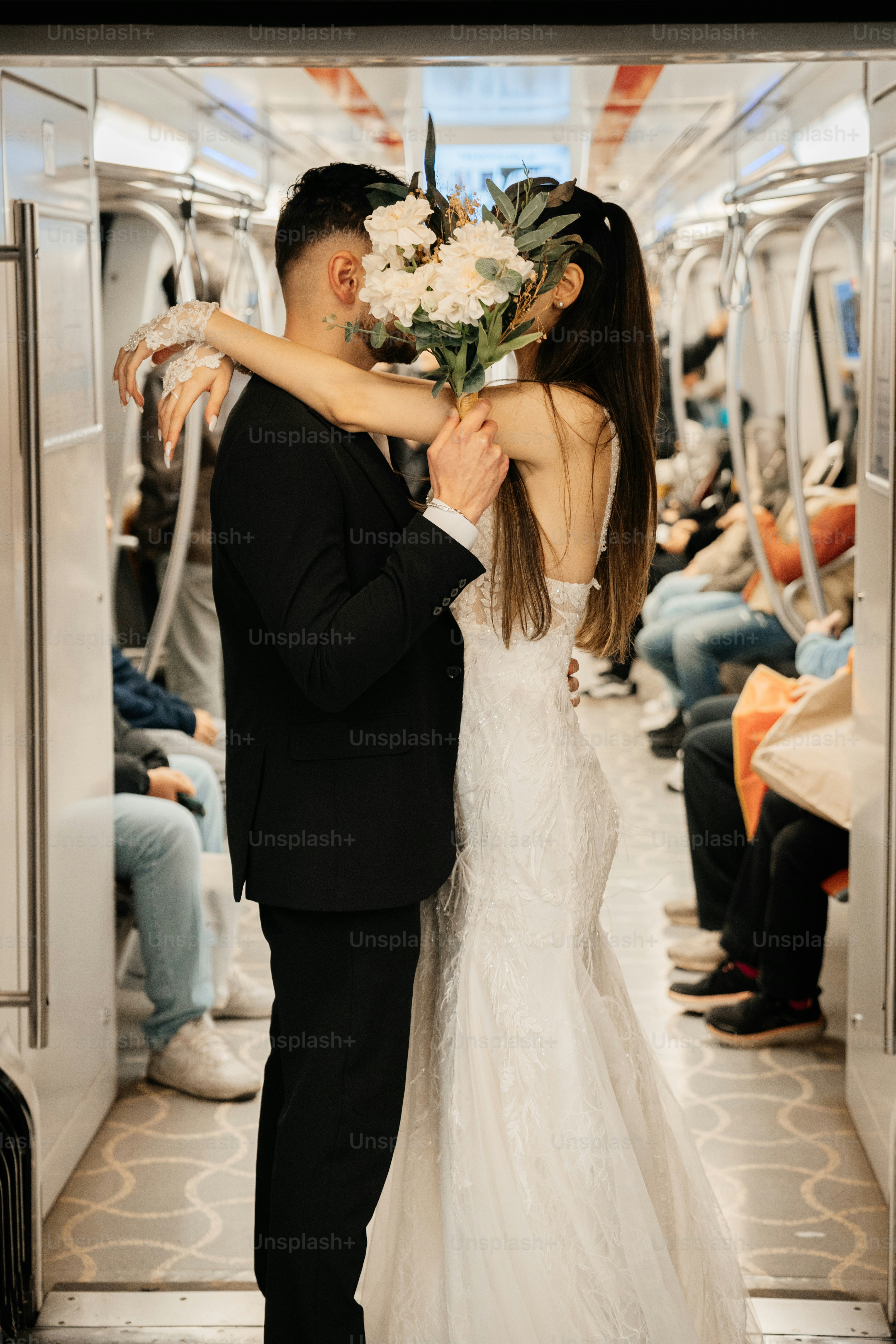 Bride and groom kissing inside a subway car.