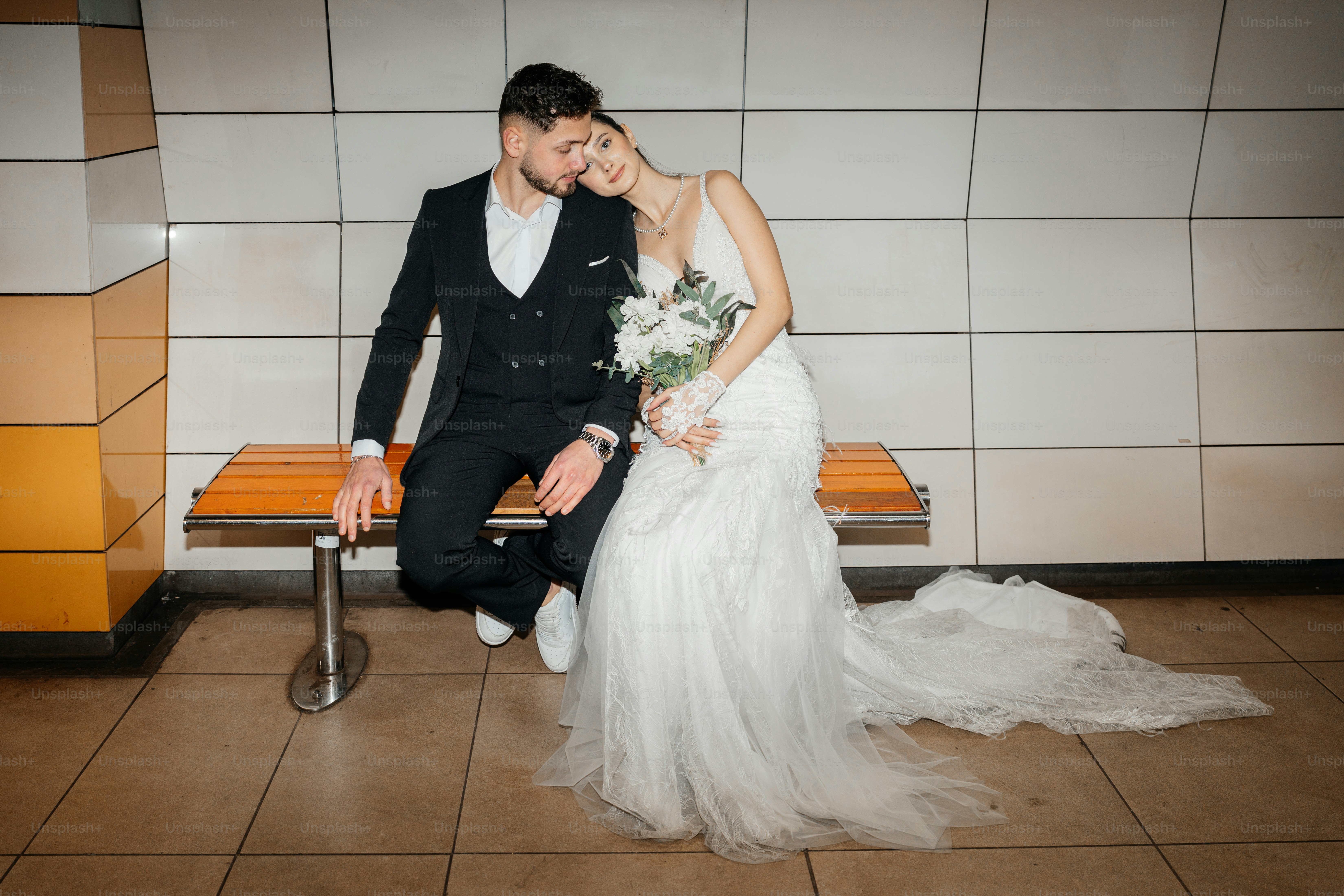 A bride and groom sit together on a bench