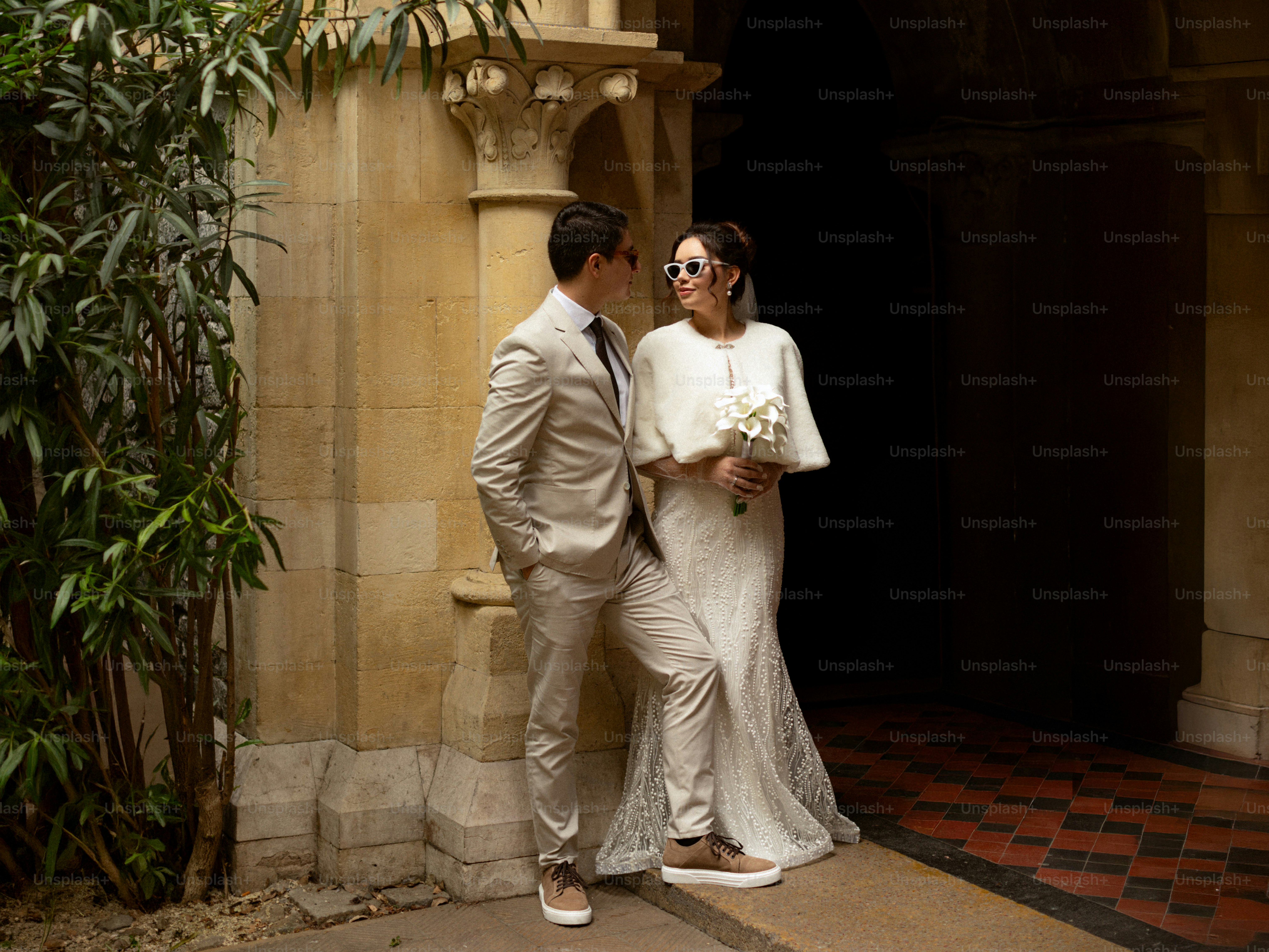 Un couple en tenue de mariage debout ensemble dehors.
