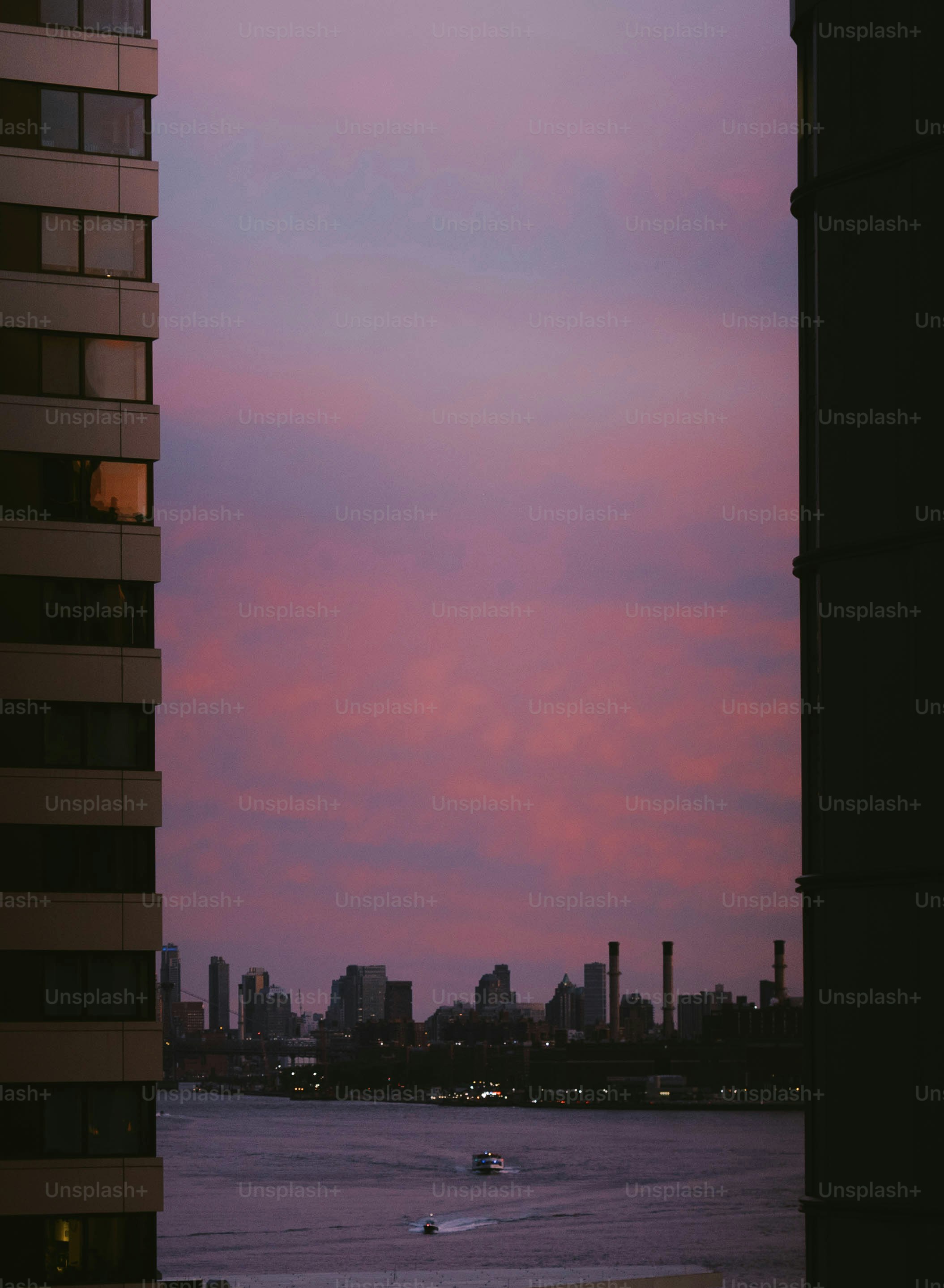 Stadtsilhouette bei Einbruch der Dämmerung mit violettem Himmel und Booten.