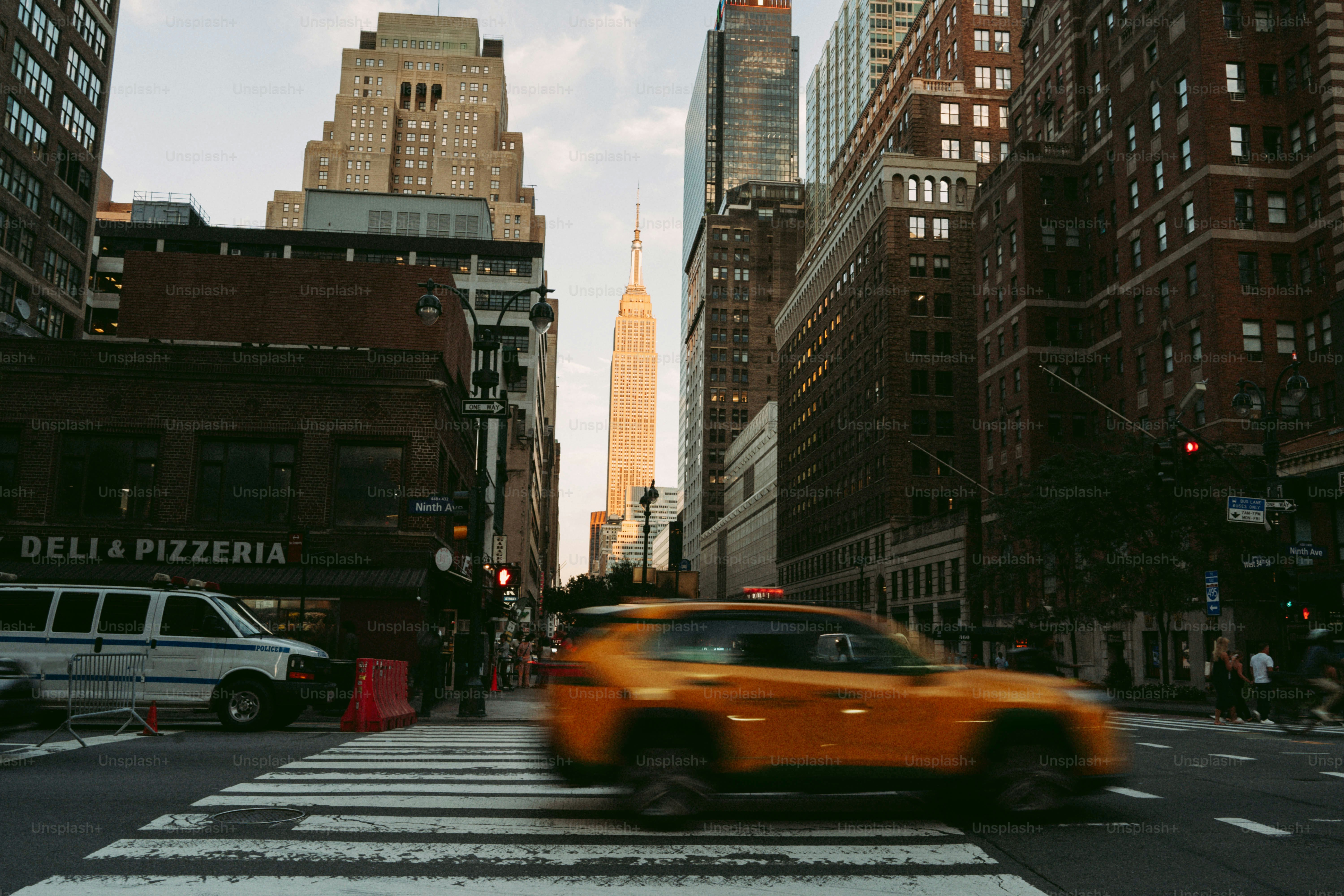 Yellow taxi crosses street in front of empire state building.