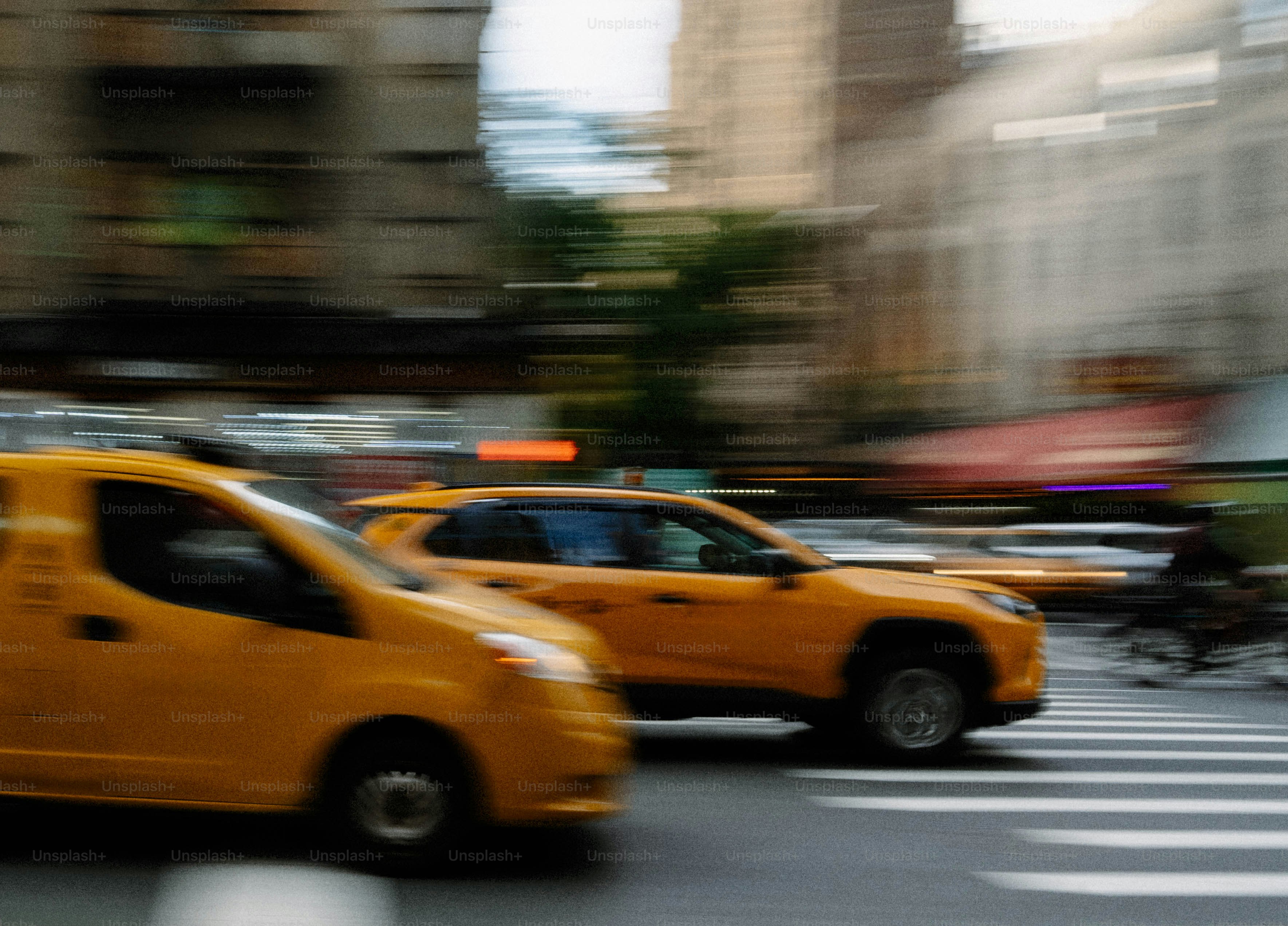 Two yellow taxis driving on a city street
