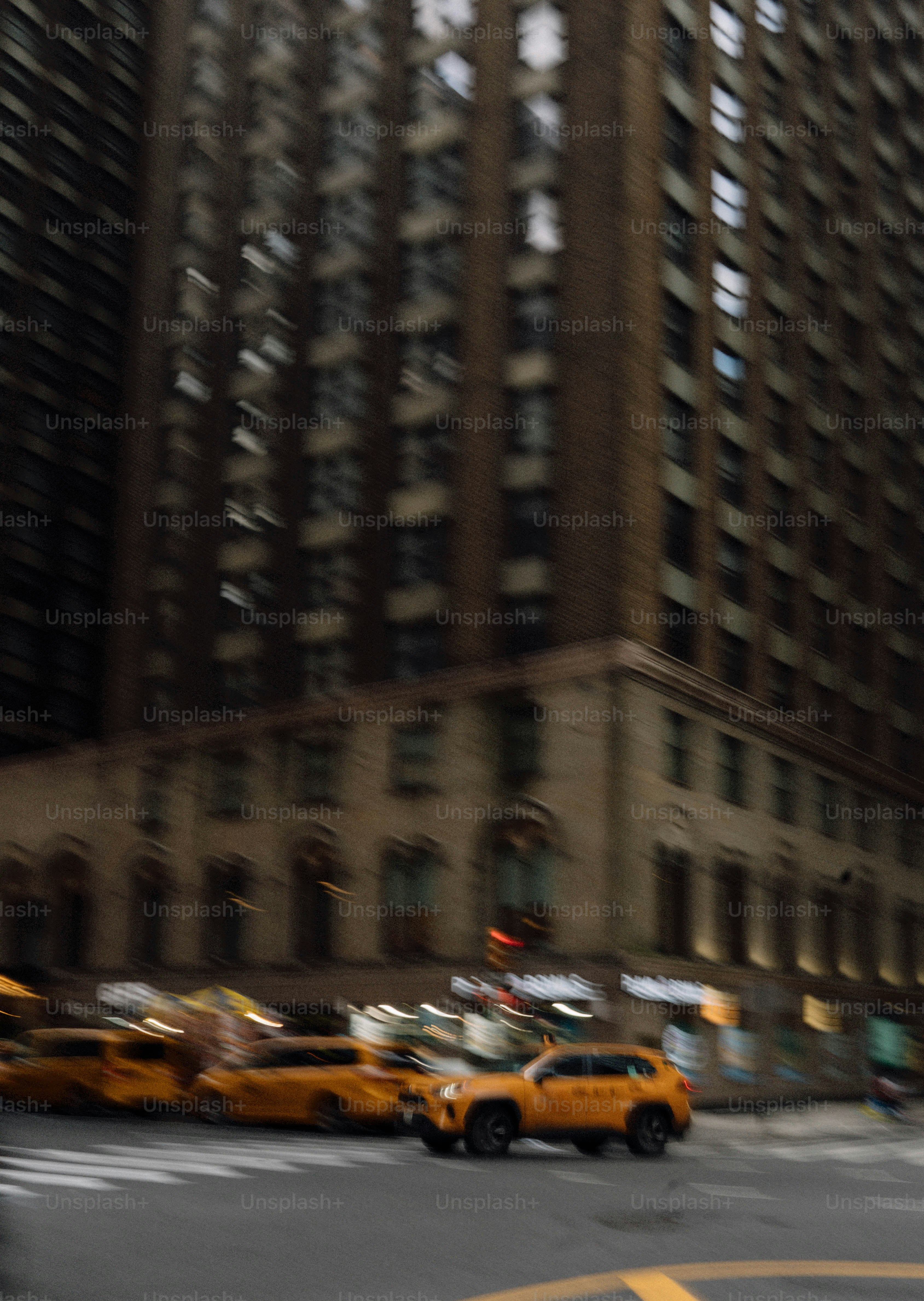 Des taxis jaunes passent devant de grands immeubles en ville.