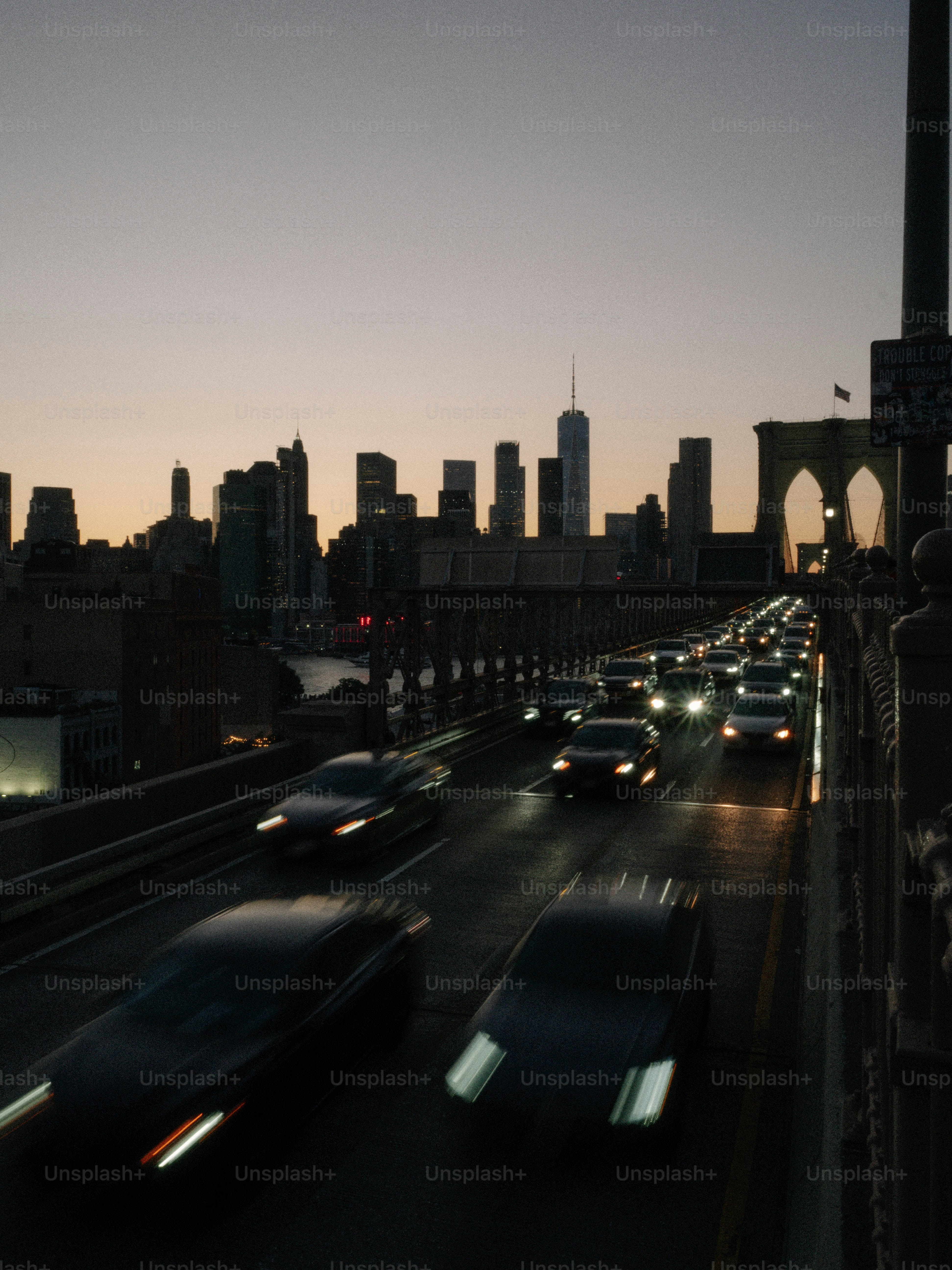 夕暮れ時に街のスカイラインへ向かう橋を走る車