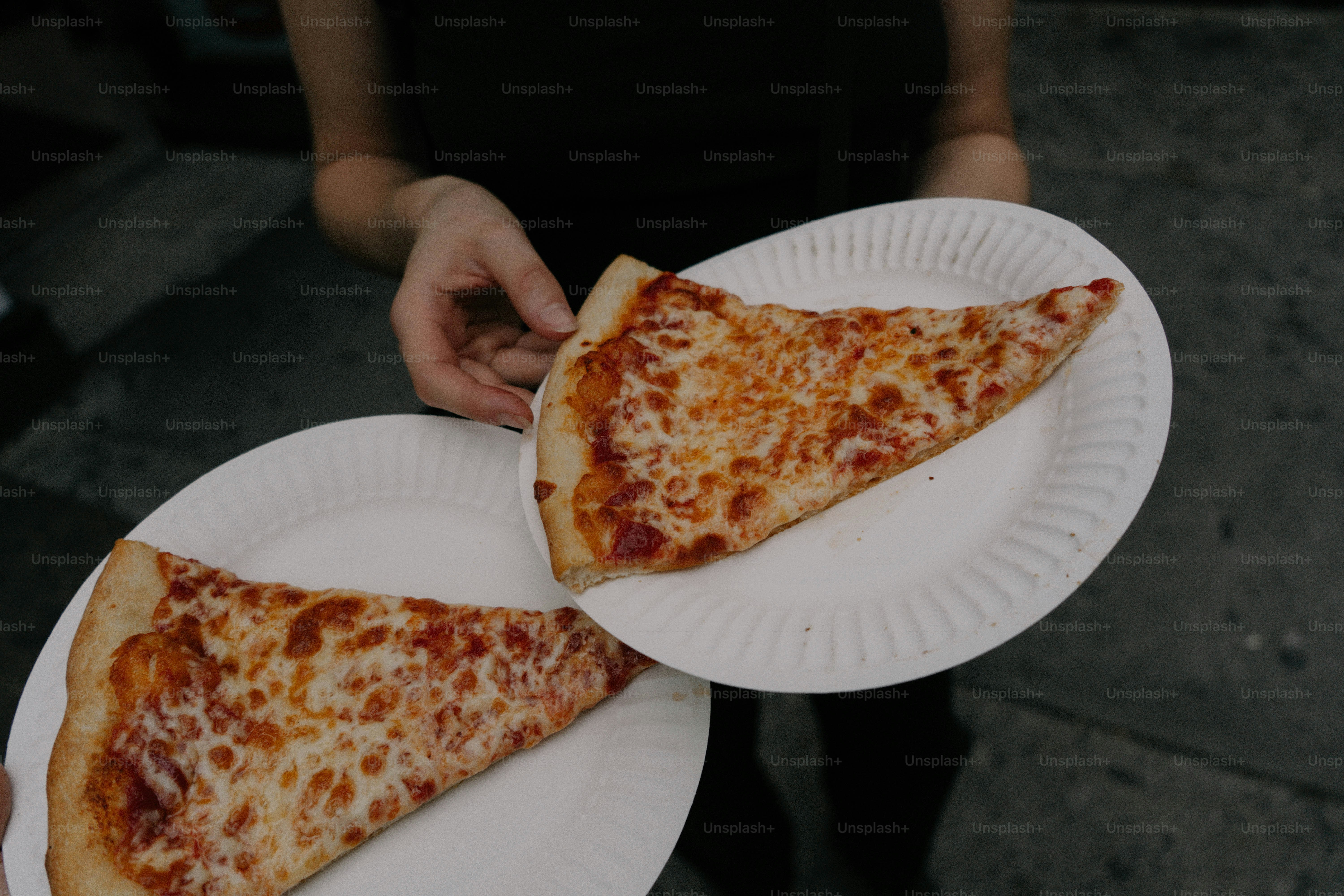Deux parts de pizza au fromage sur des assiettes en papier
