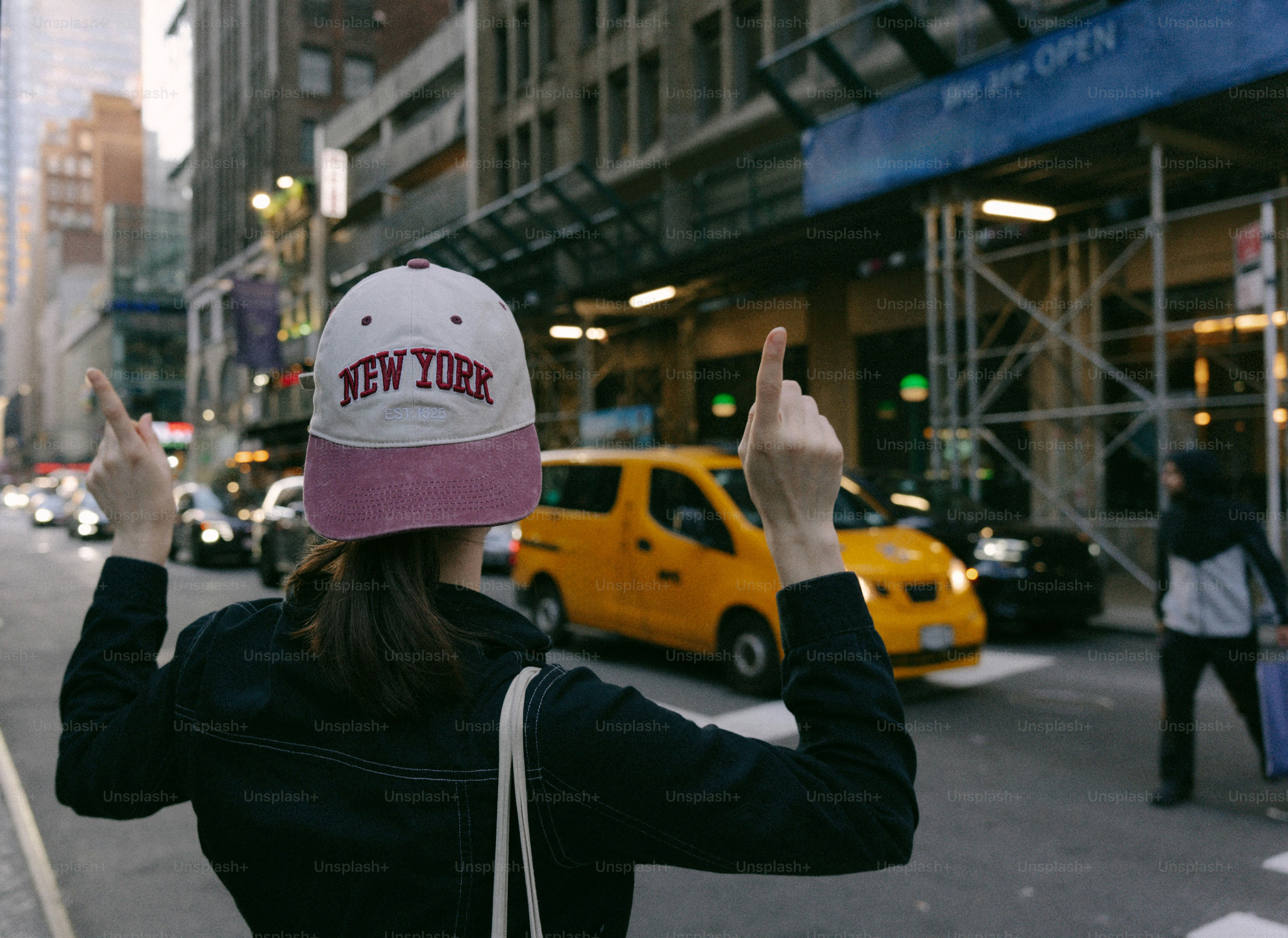 Woman in new york city points up with both hands.