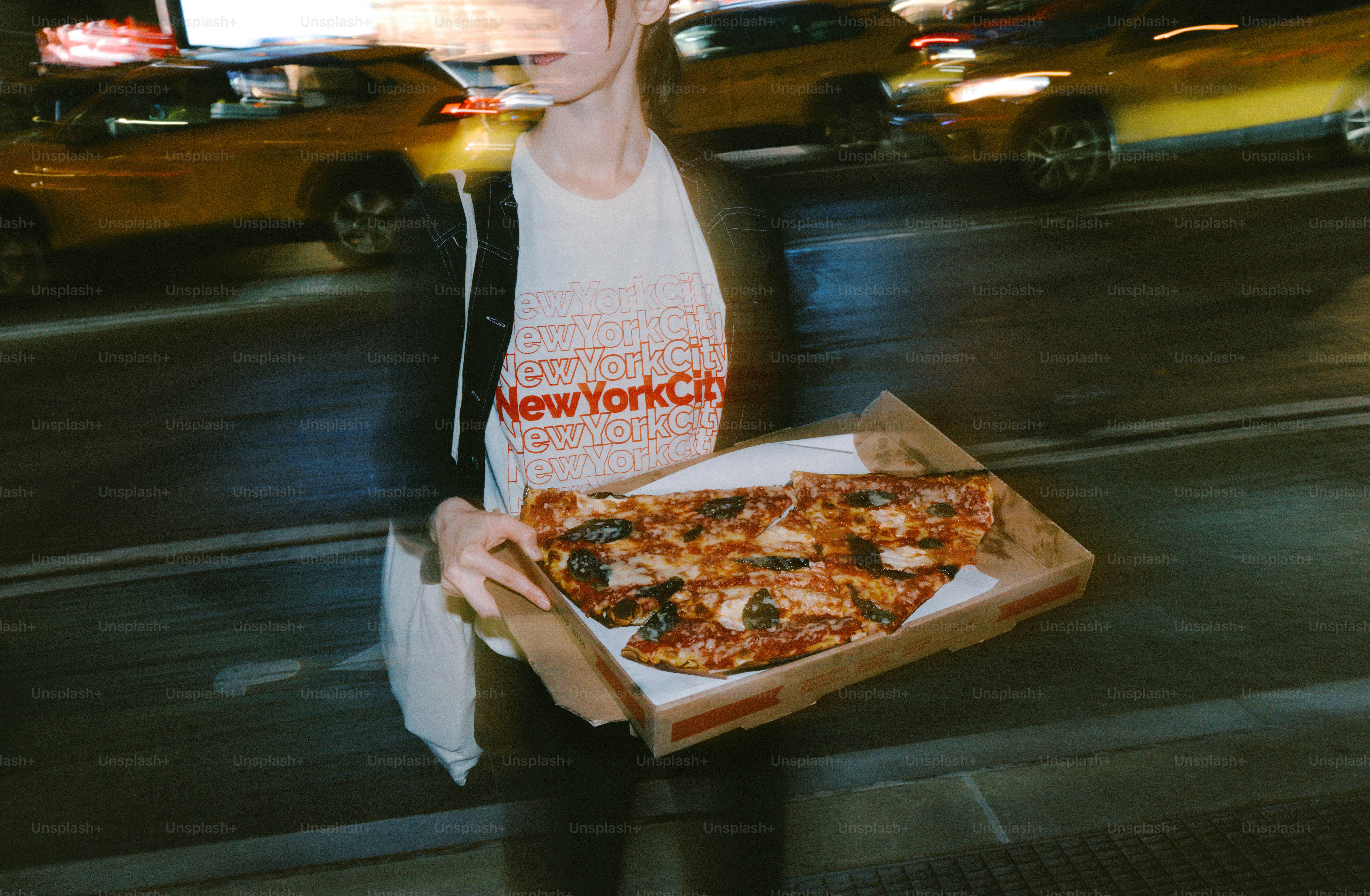 Woman holding a pizza box on a city street