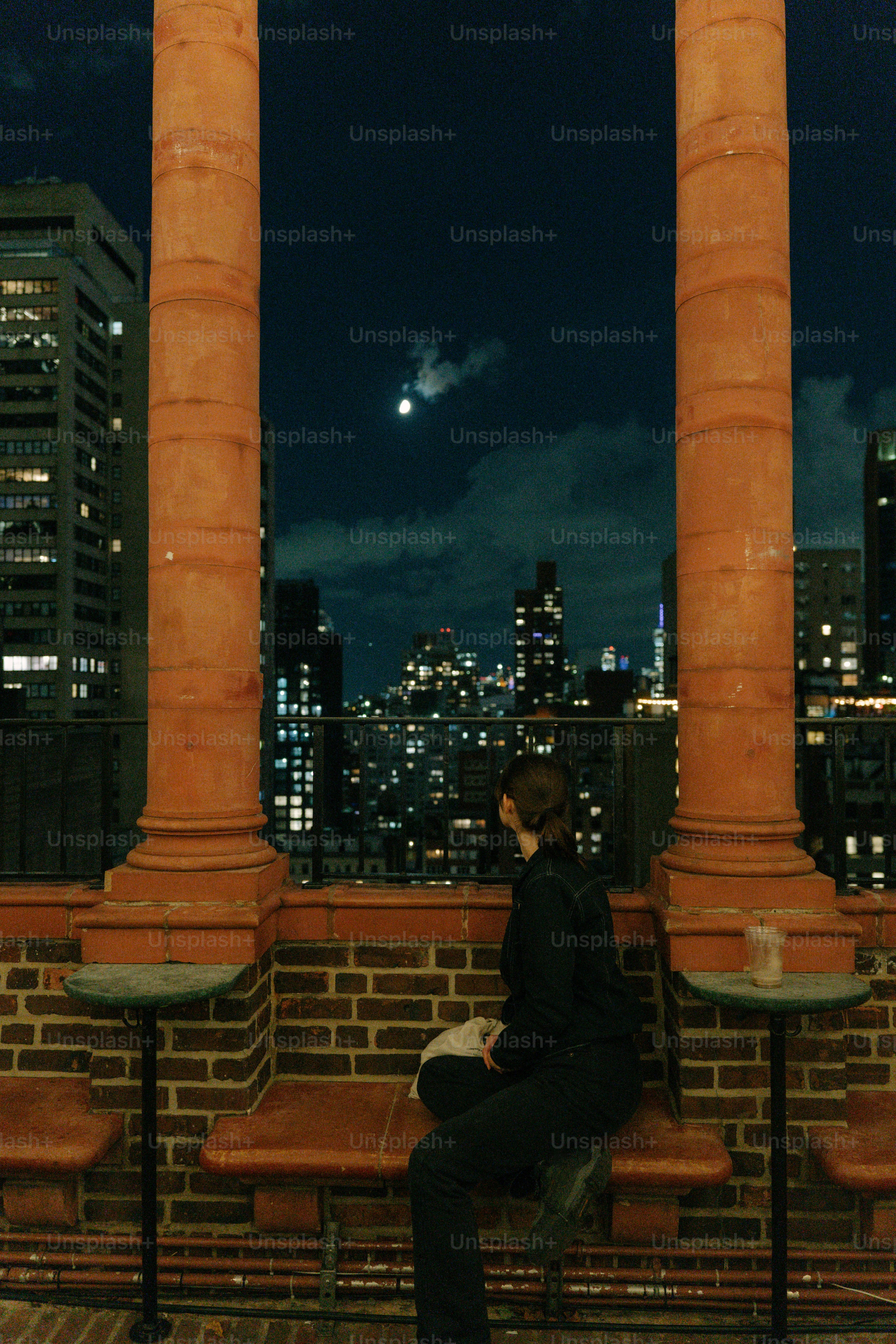 Femme regardant les lumières de la ville la nuit depuis le toit