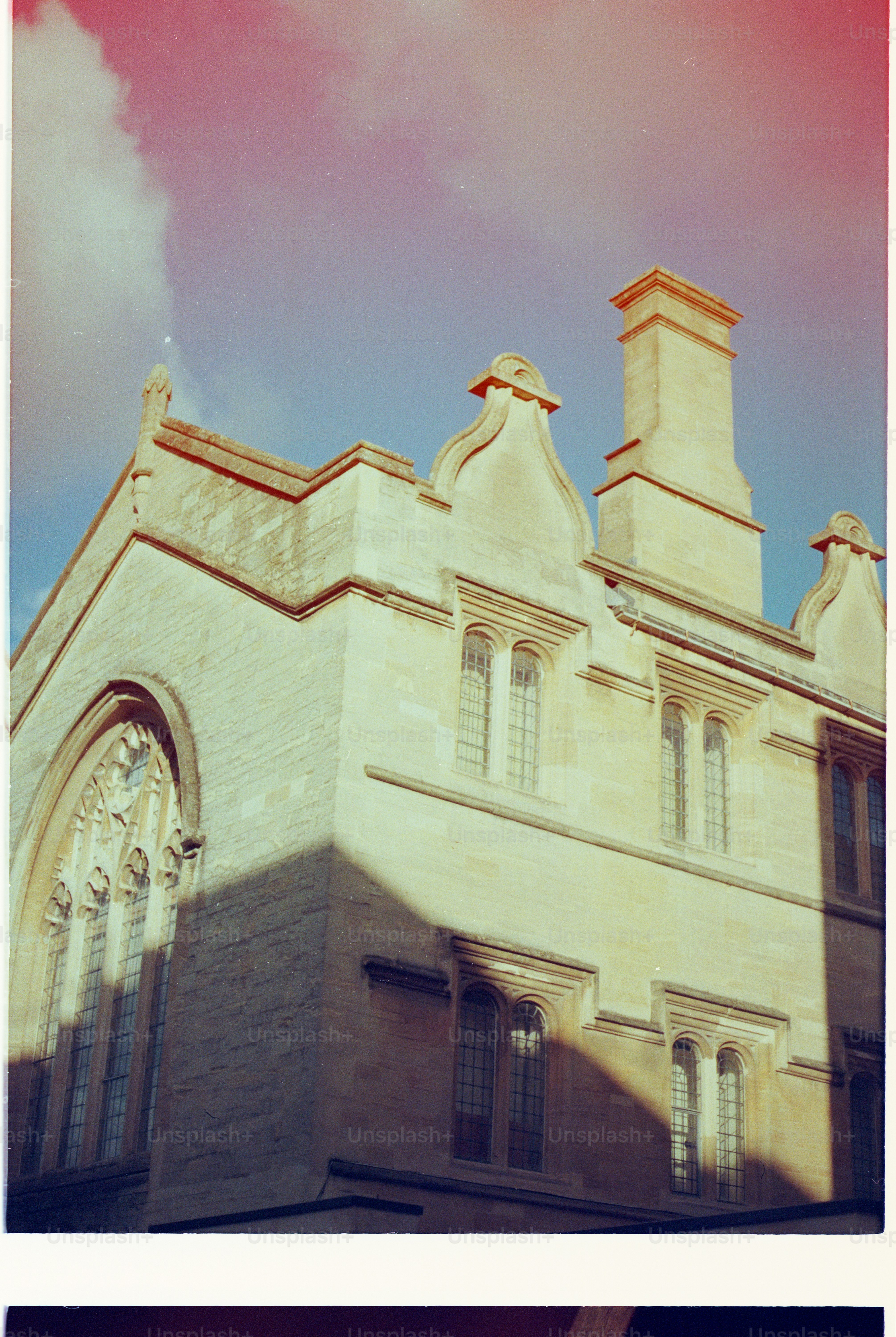 Historic stone building with ornate windows and chimney.