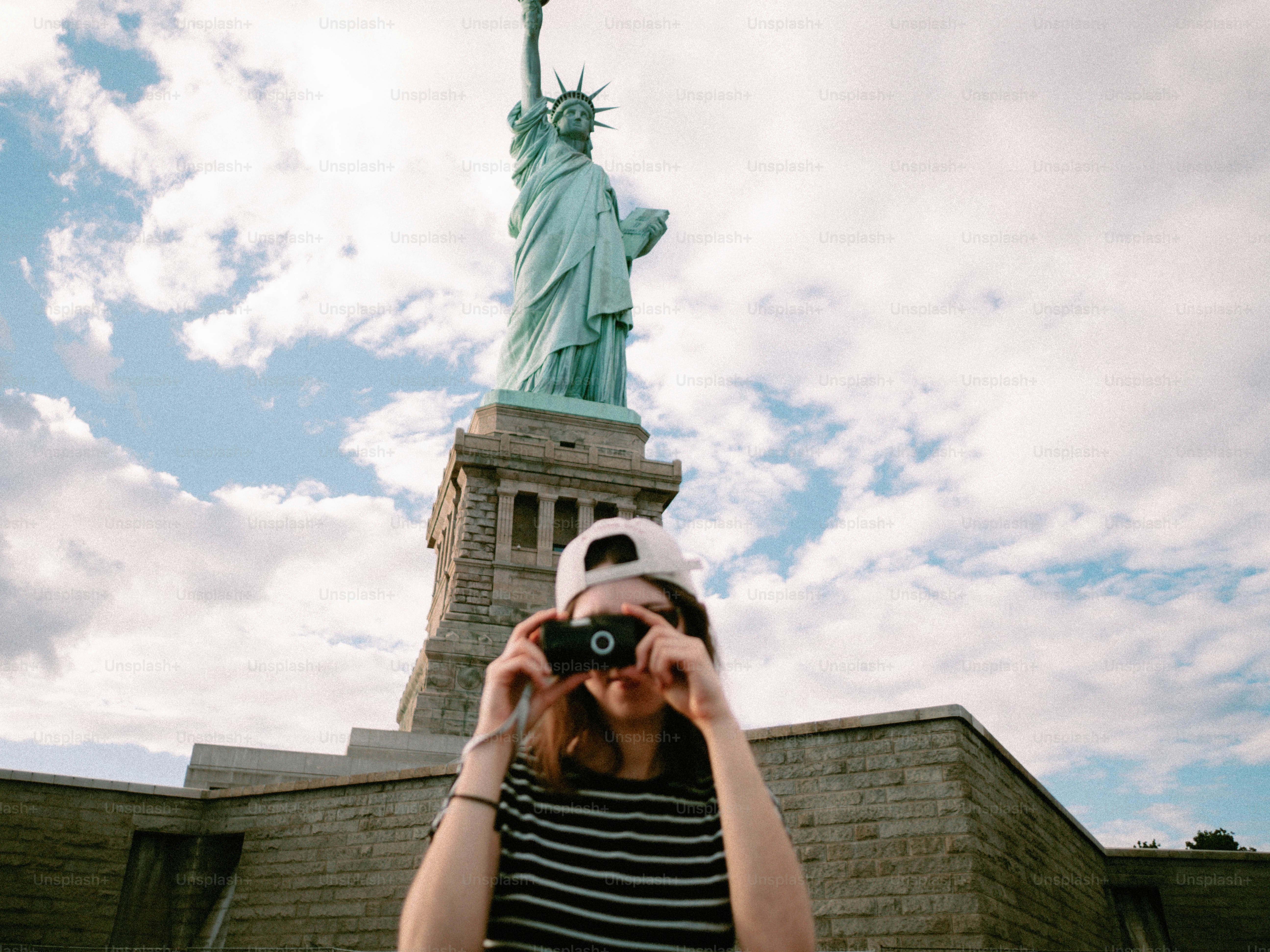 Woman taking a picture of the statue of liberty.