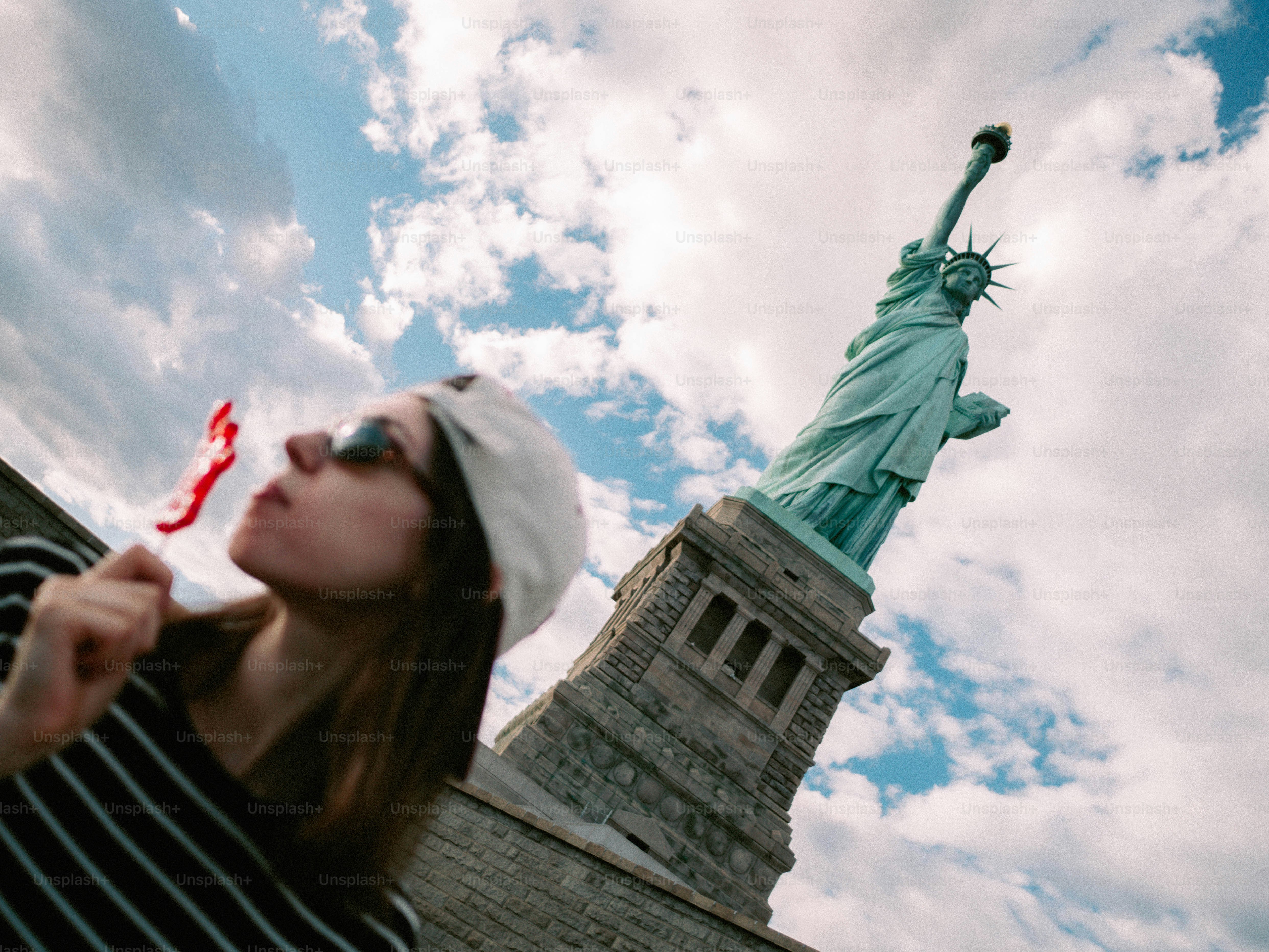 Mujer comiendo piruleta con la Estatua de la Libertad detrás