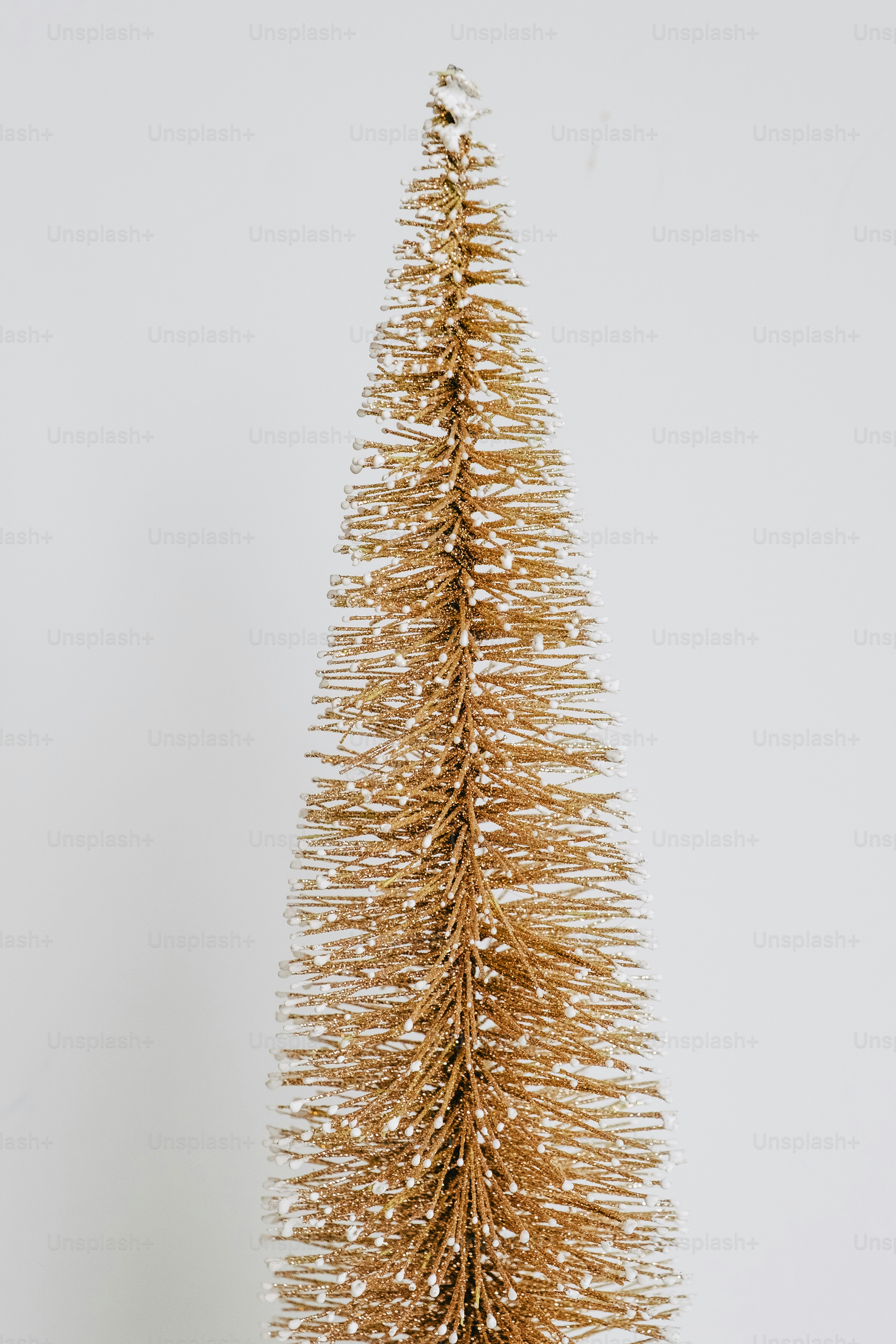 A tall, slender, gold, glitter-covered artificial christmas tree.