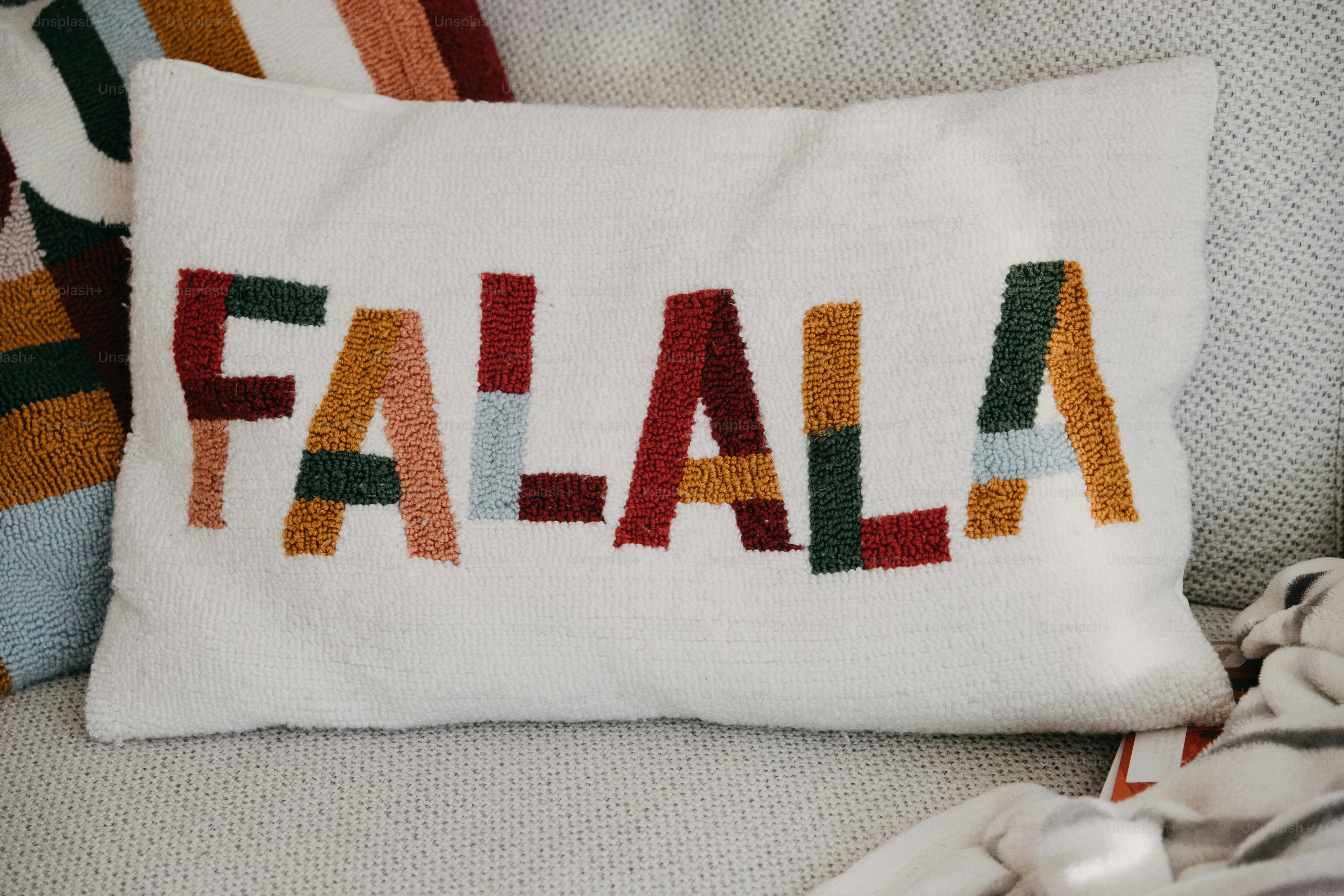 White pillow with colorful "fa la la" text