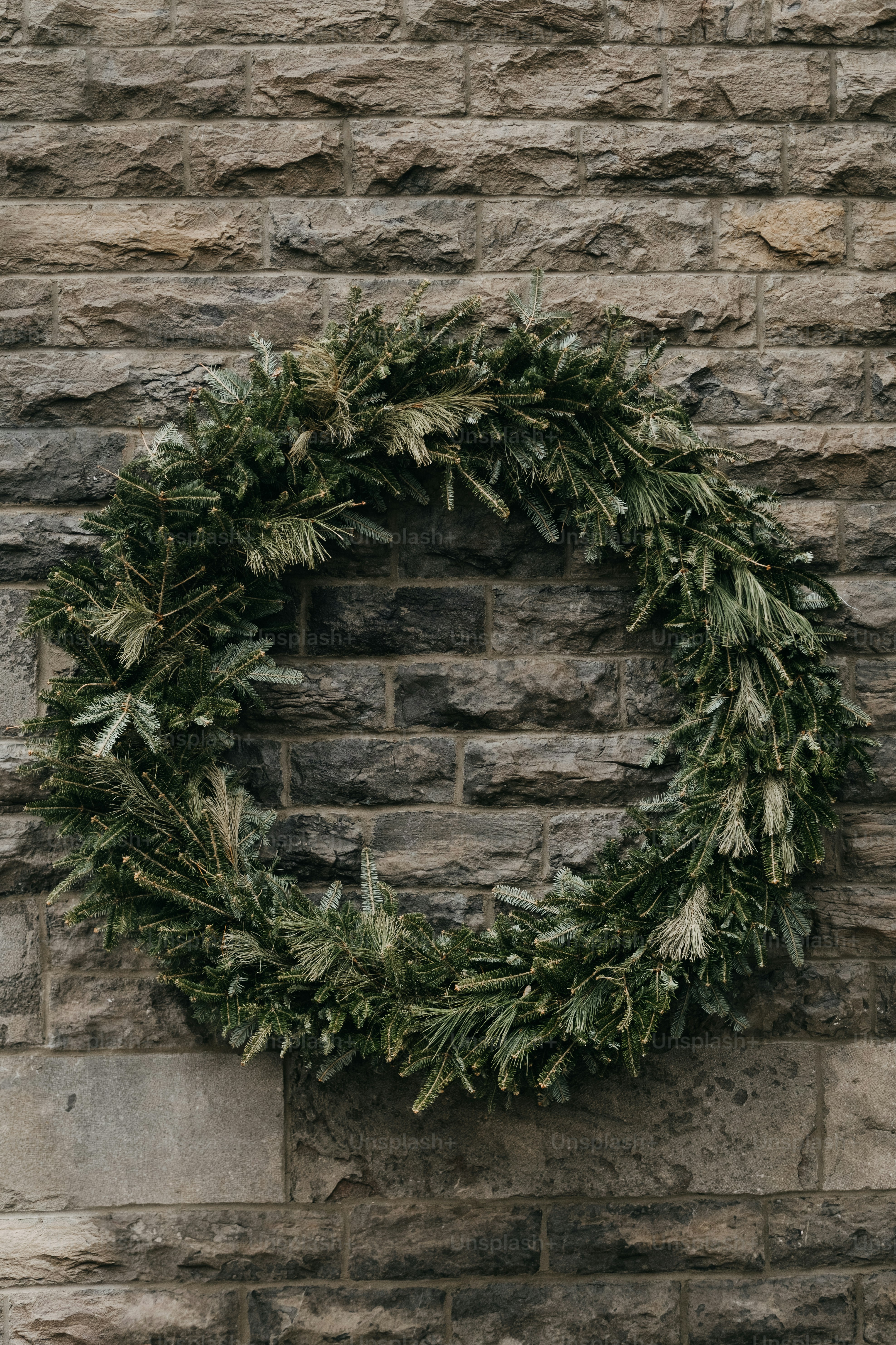 A green wreath hangs on a stone wall.