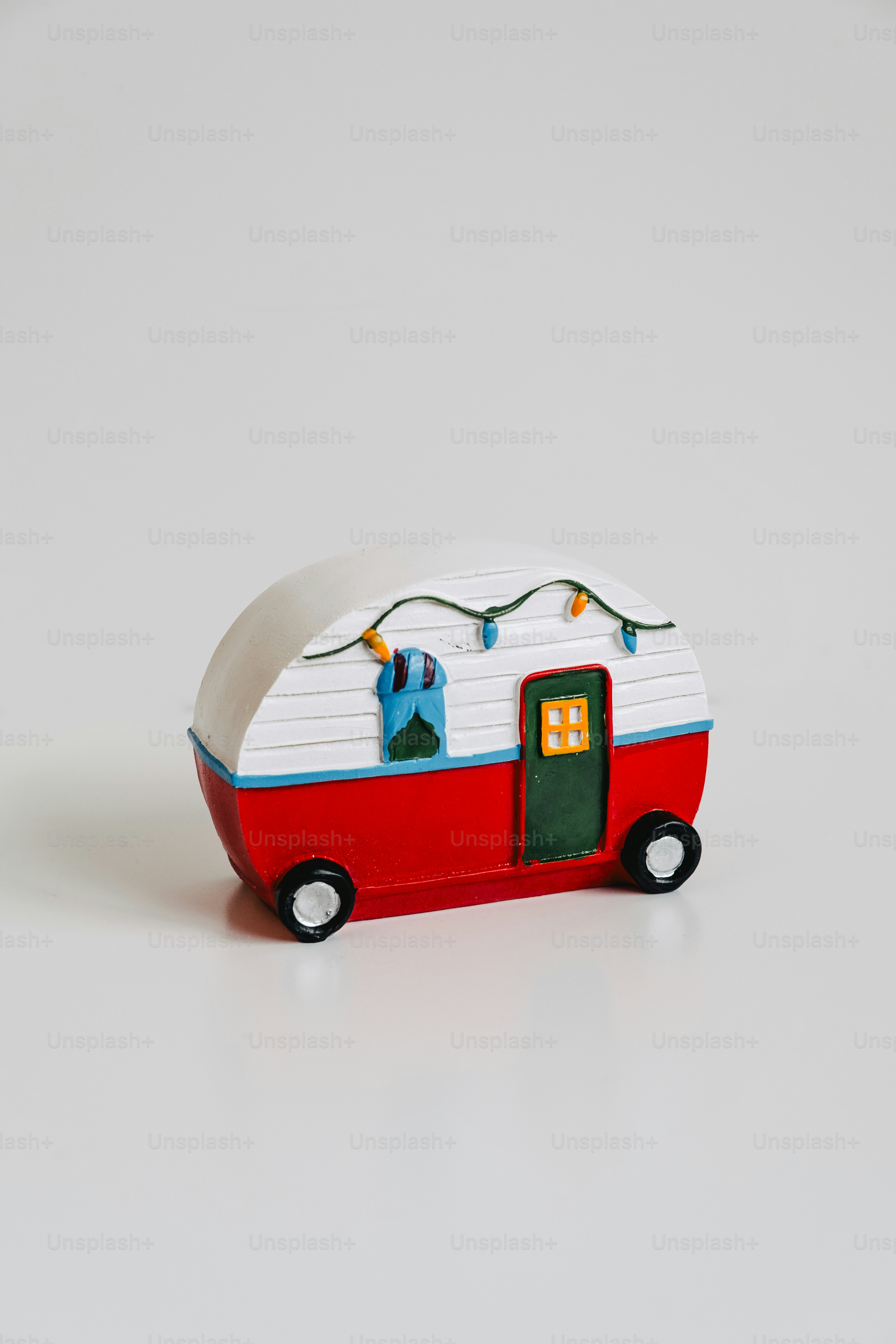 A small red and white camper with holiday lights.