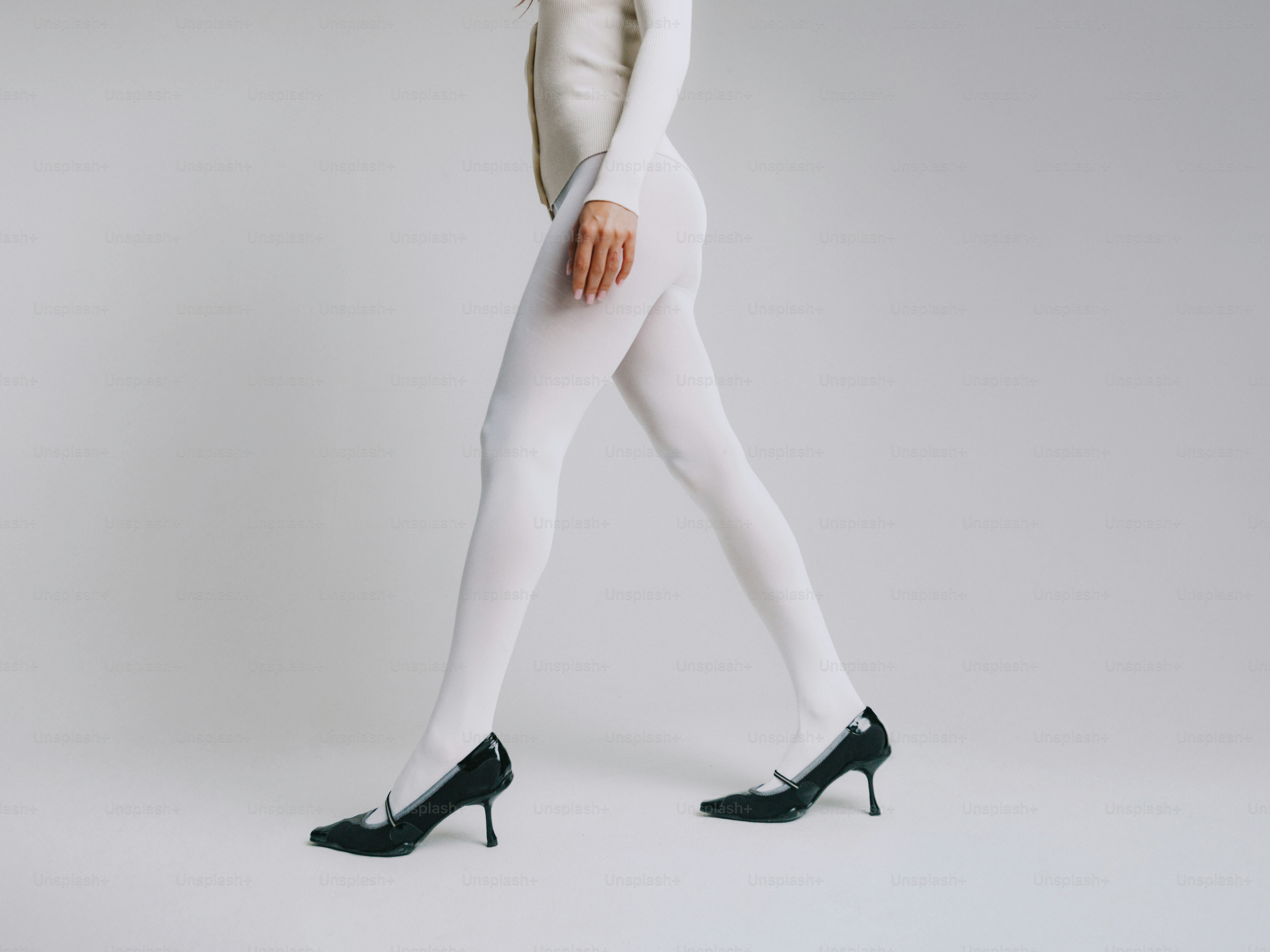 Donna che cammina con collant bianchi e tacchi neri