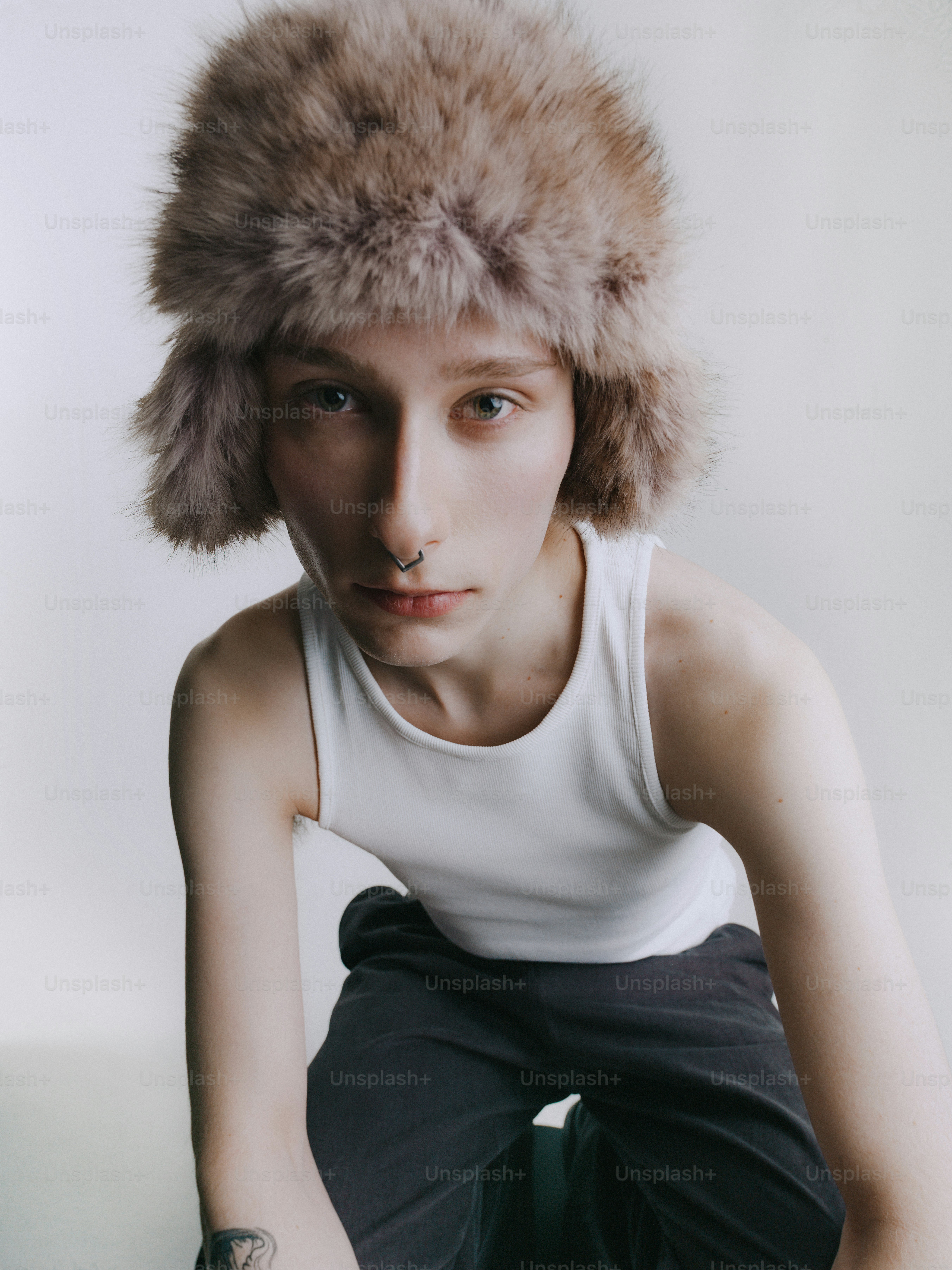 Young person wearing a fluffy hat and tank top.