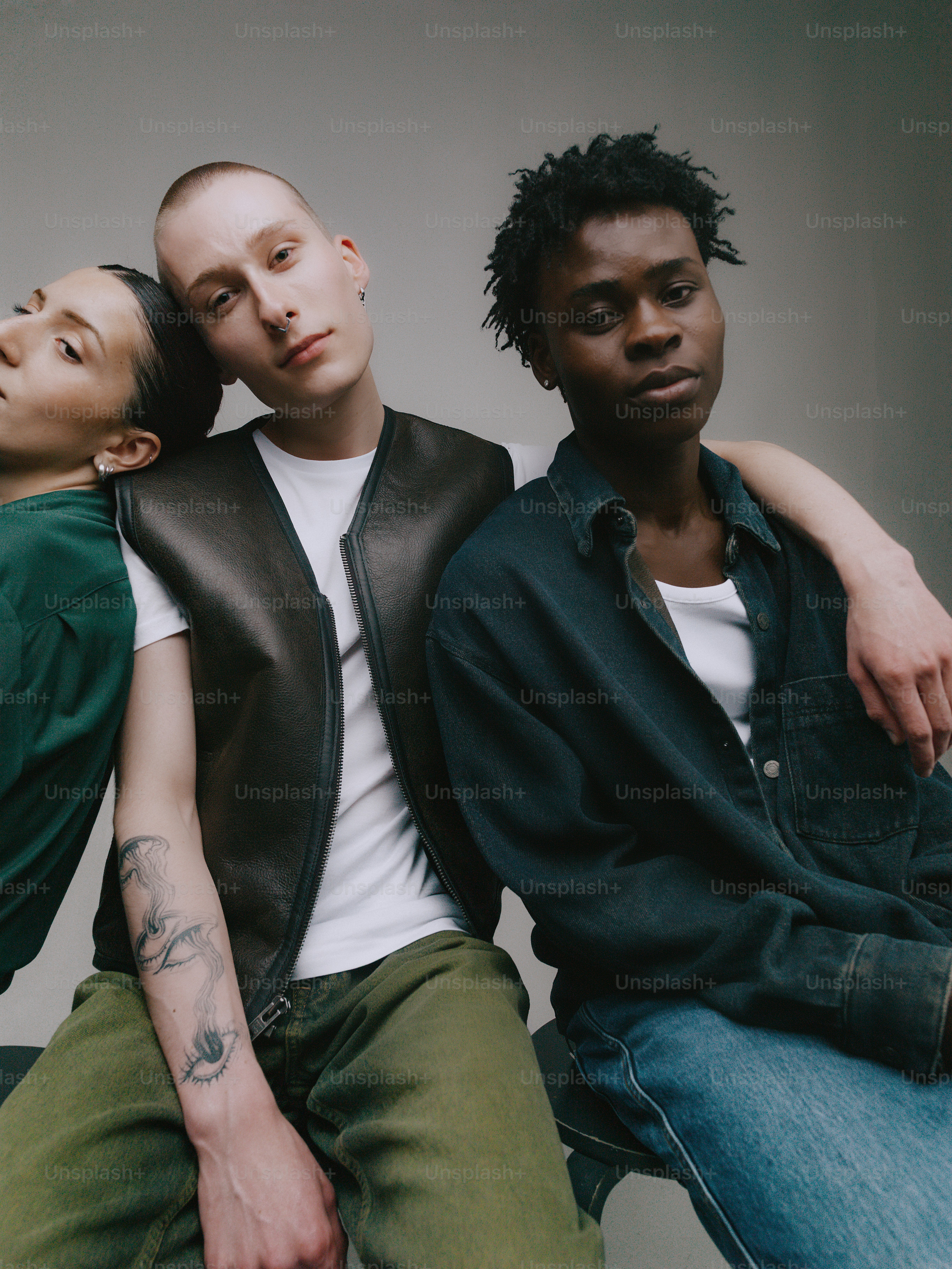 Three diverse people posing together against a grey background.