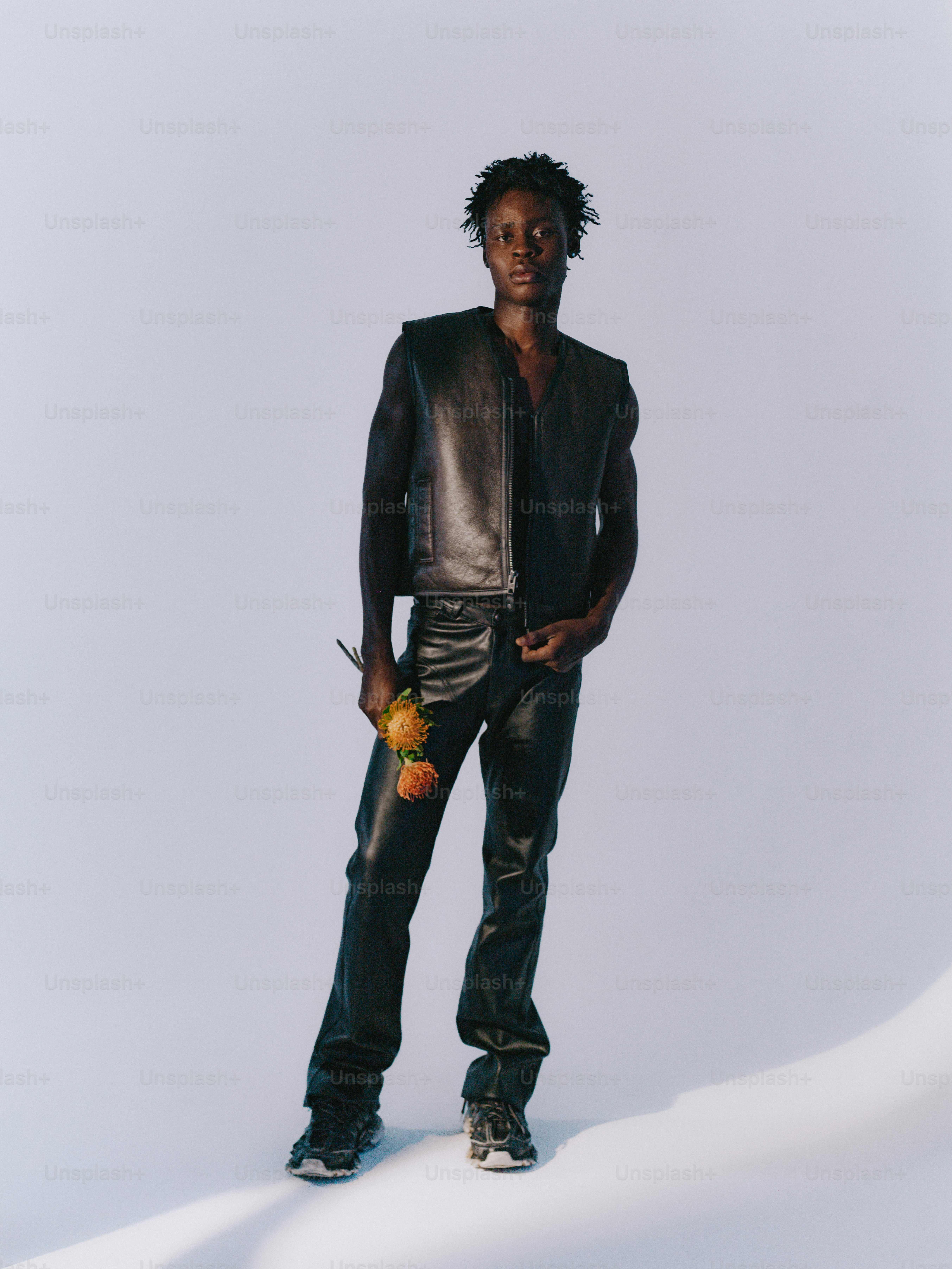 Homme en gilet et pantalon en cuir tenant deux roses