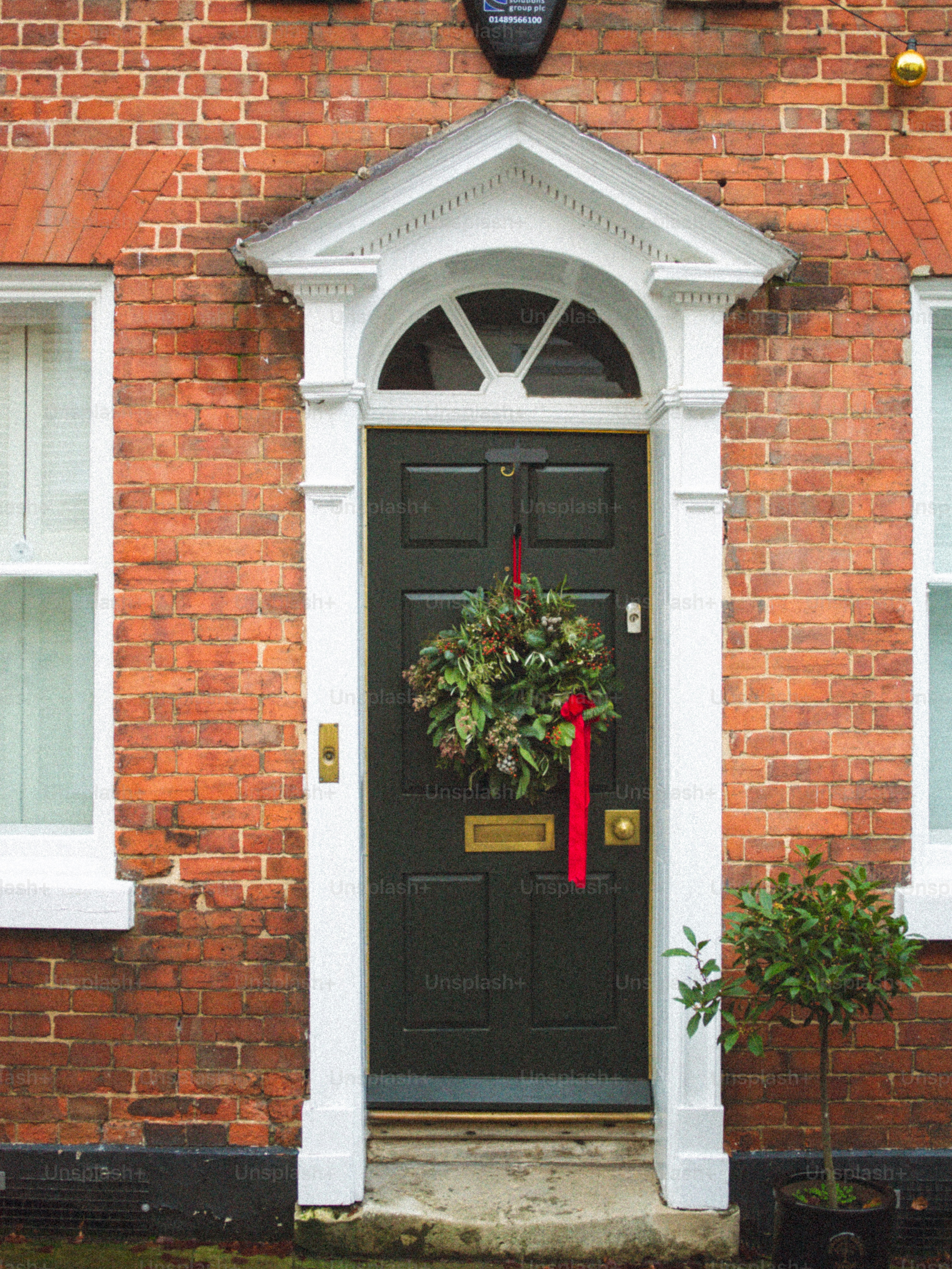 Dark green door with christmas wreath on brick house.