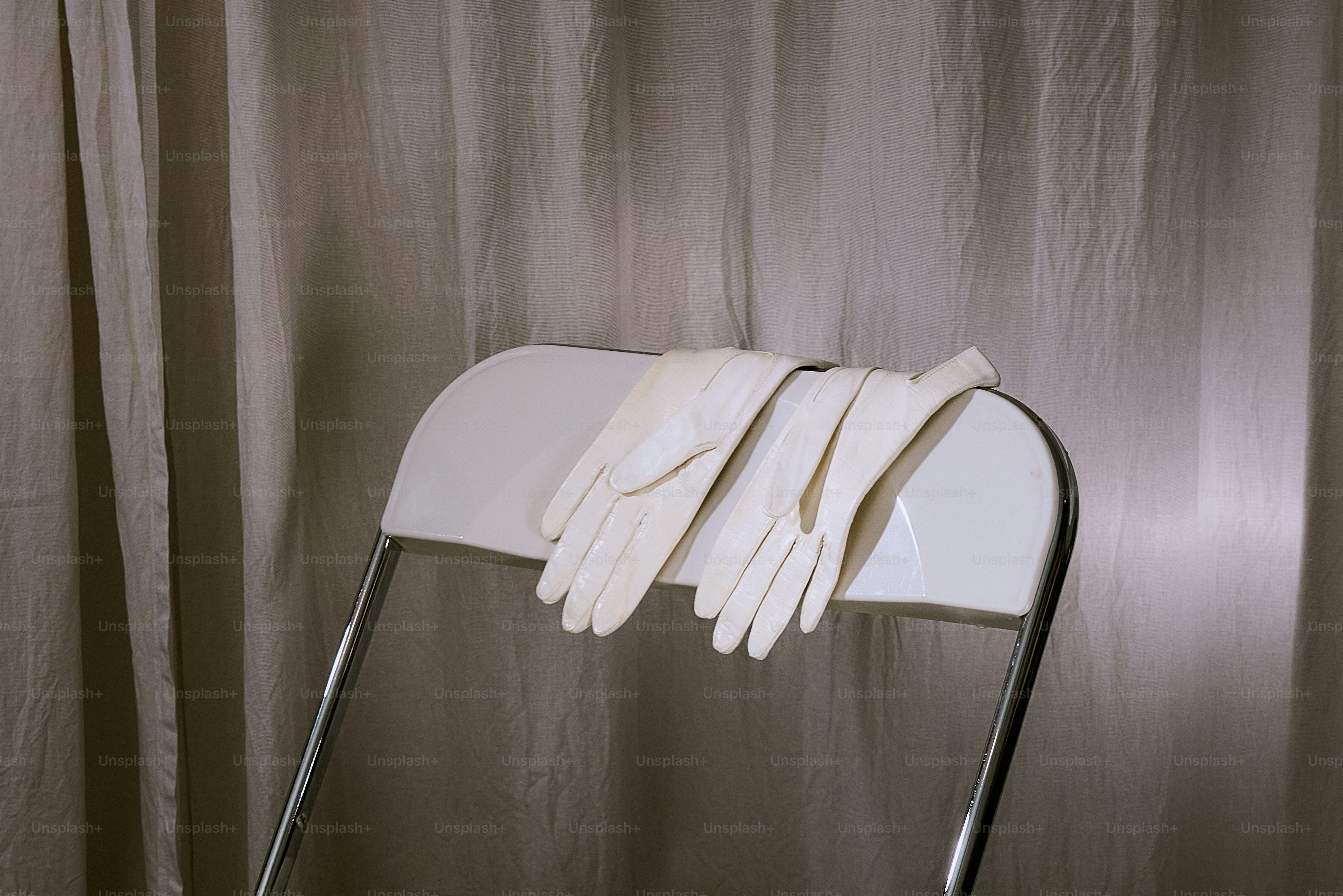 White gloves rest on a white chair.