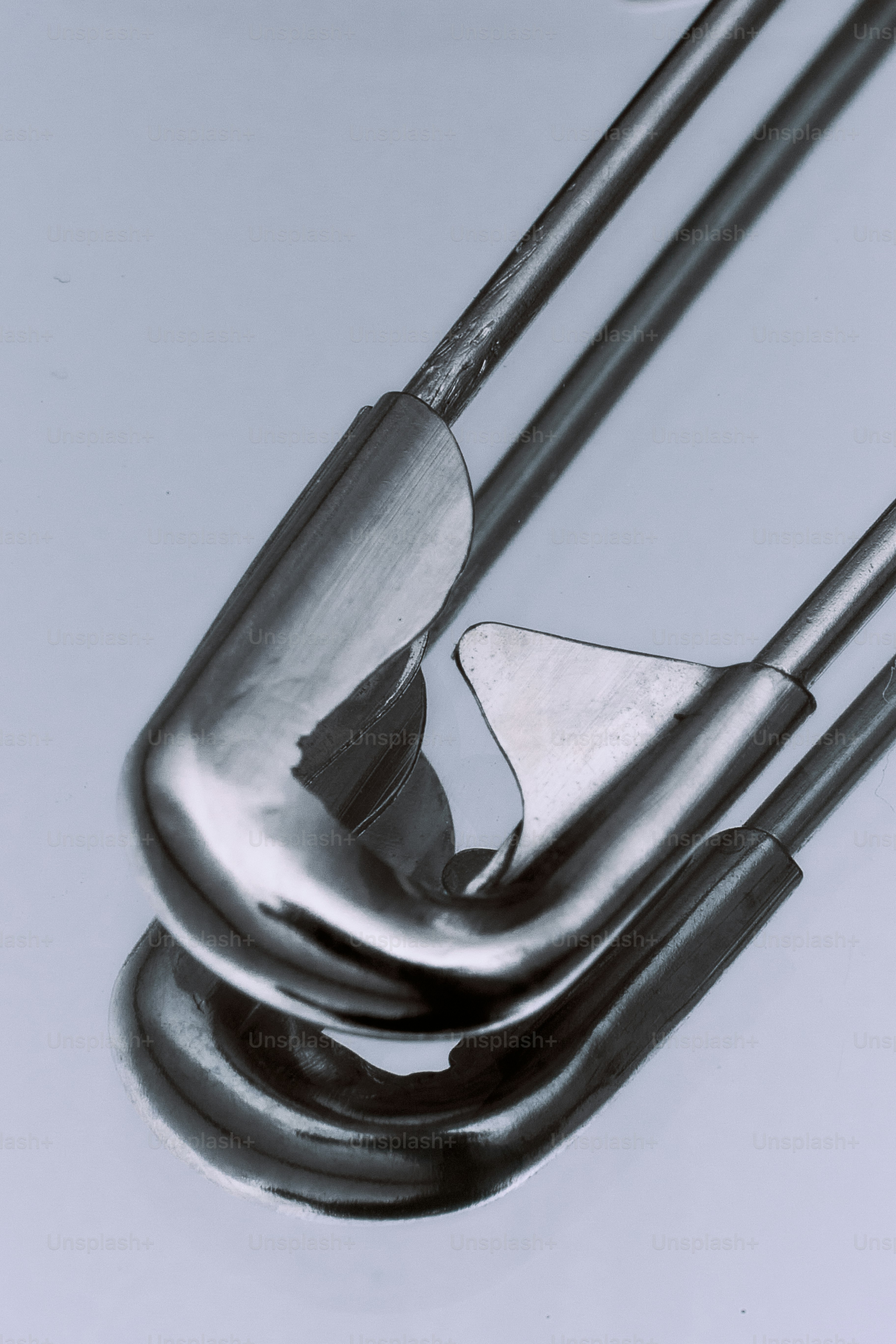 Close-up of a silver safety pin on a reflective surface