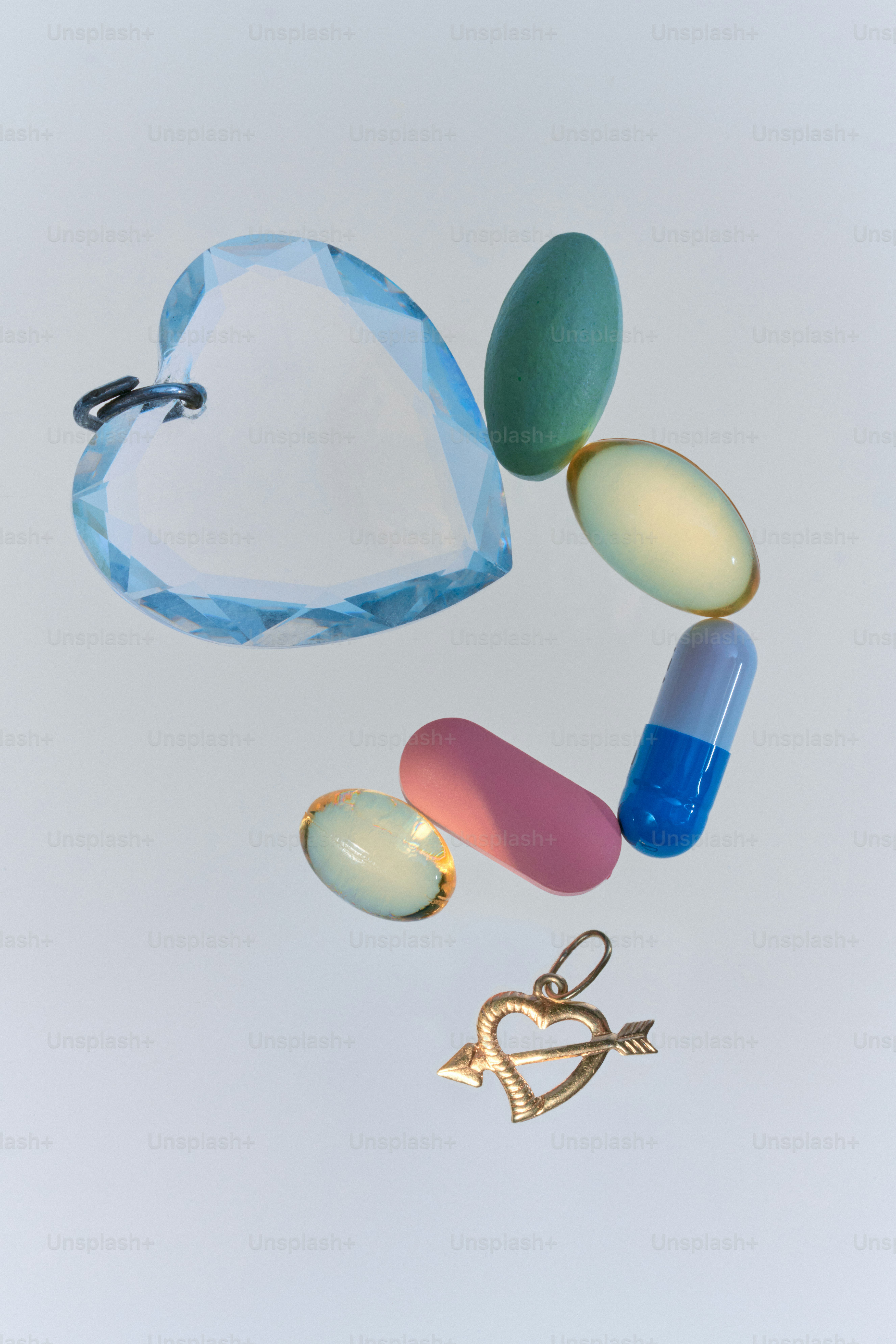 Crystal heart and gold charm surrounded by pills.