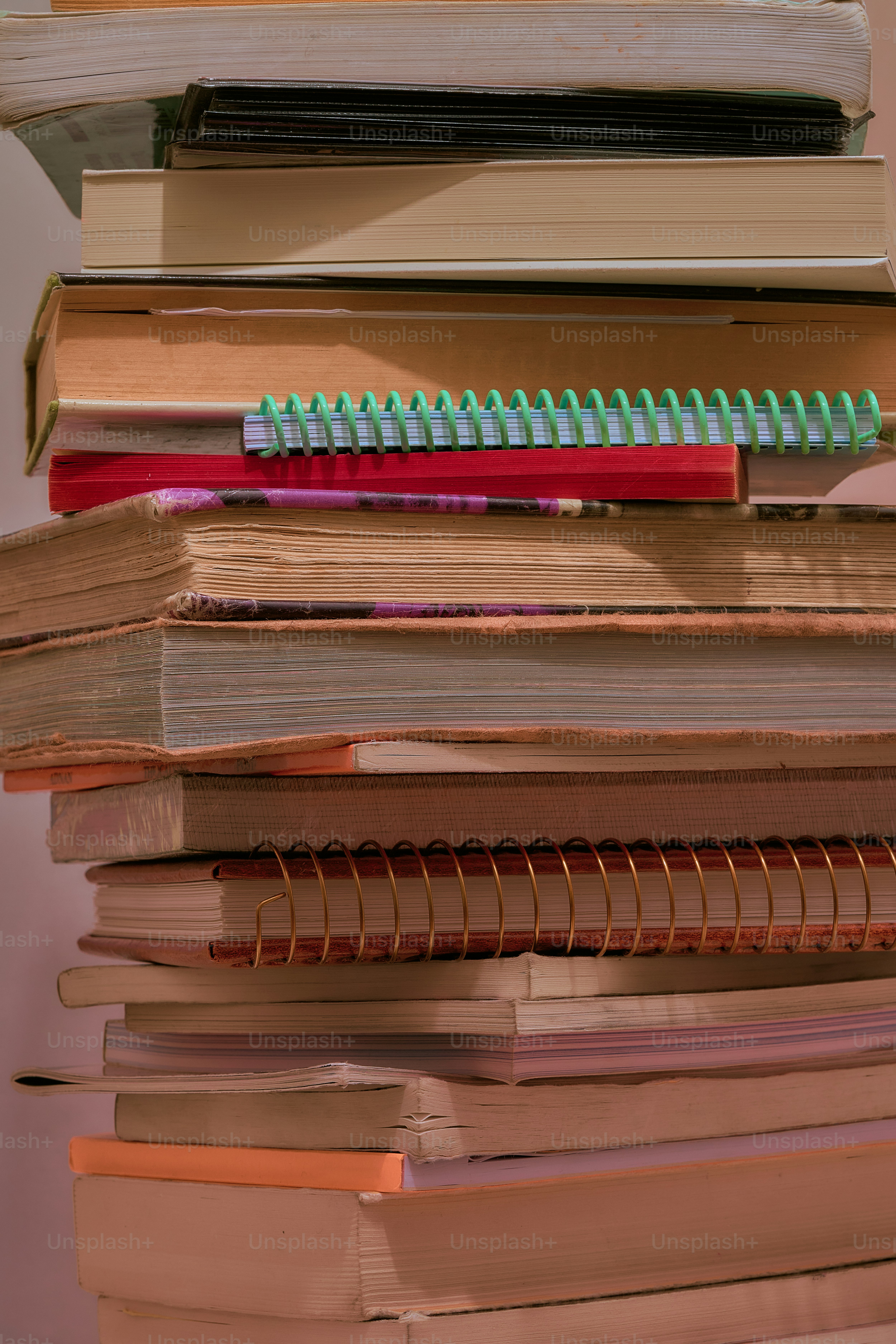 A tall stack of various books and notebooks.