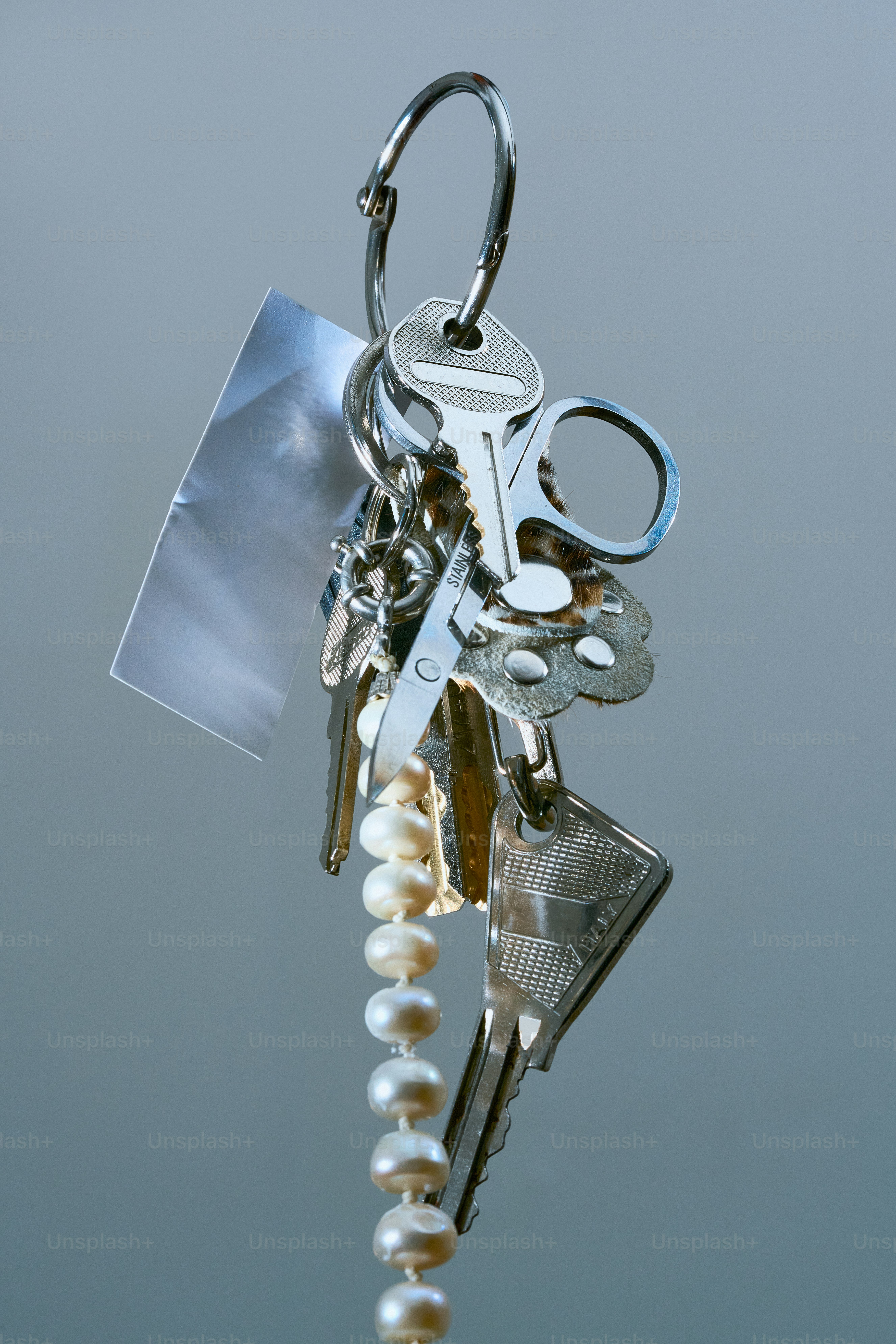 A bunch of keys with a pearl keychain.
