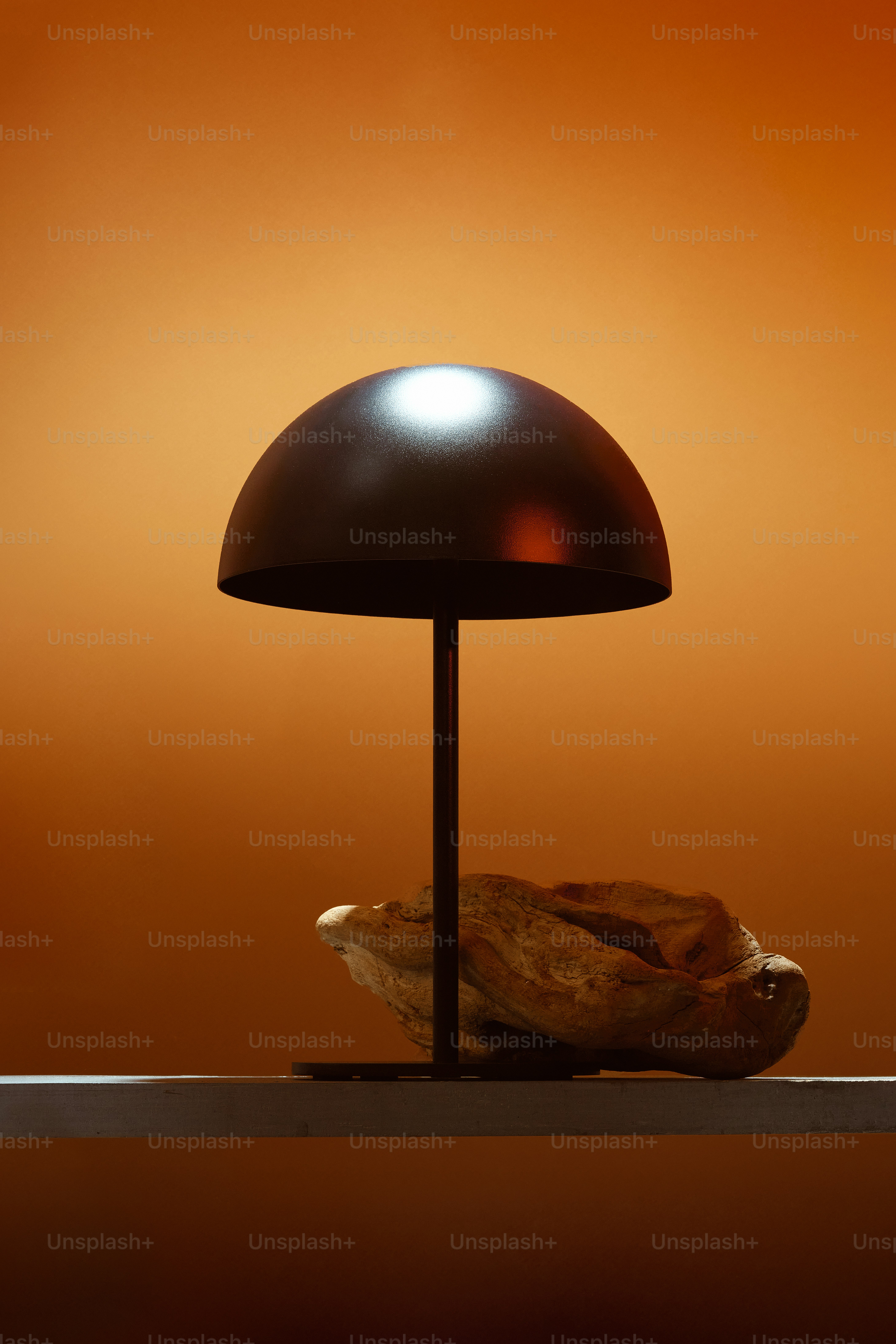 A dark dome lamp with a rock on a shelf.