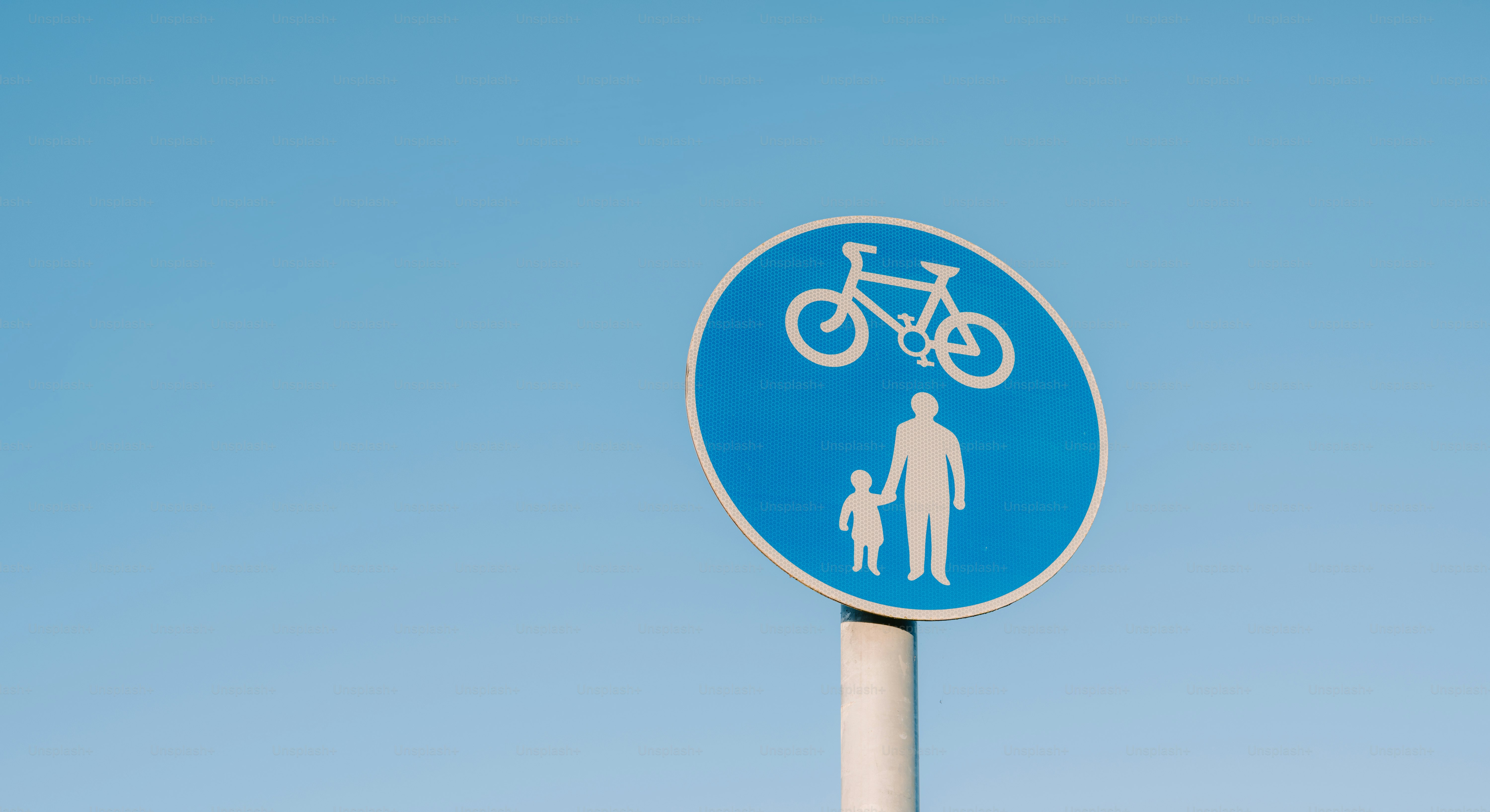 Bicycle and pedestrian path sign against blue sky