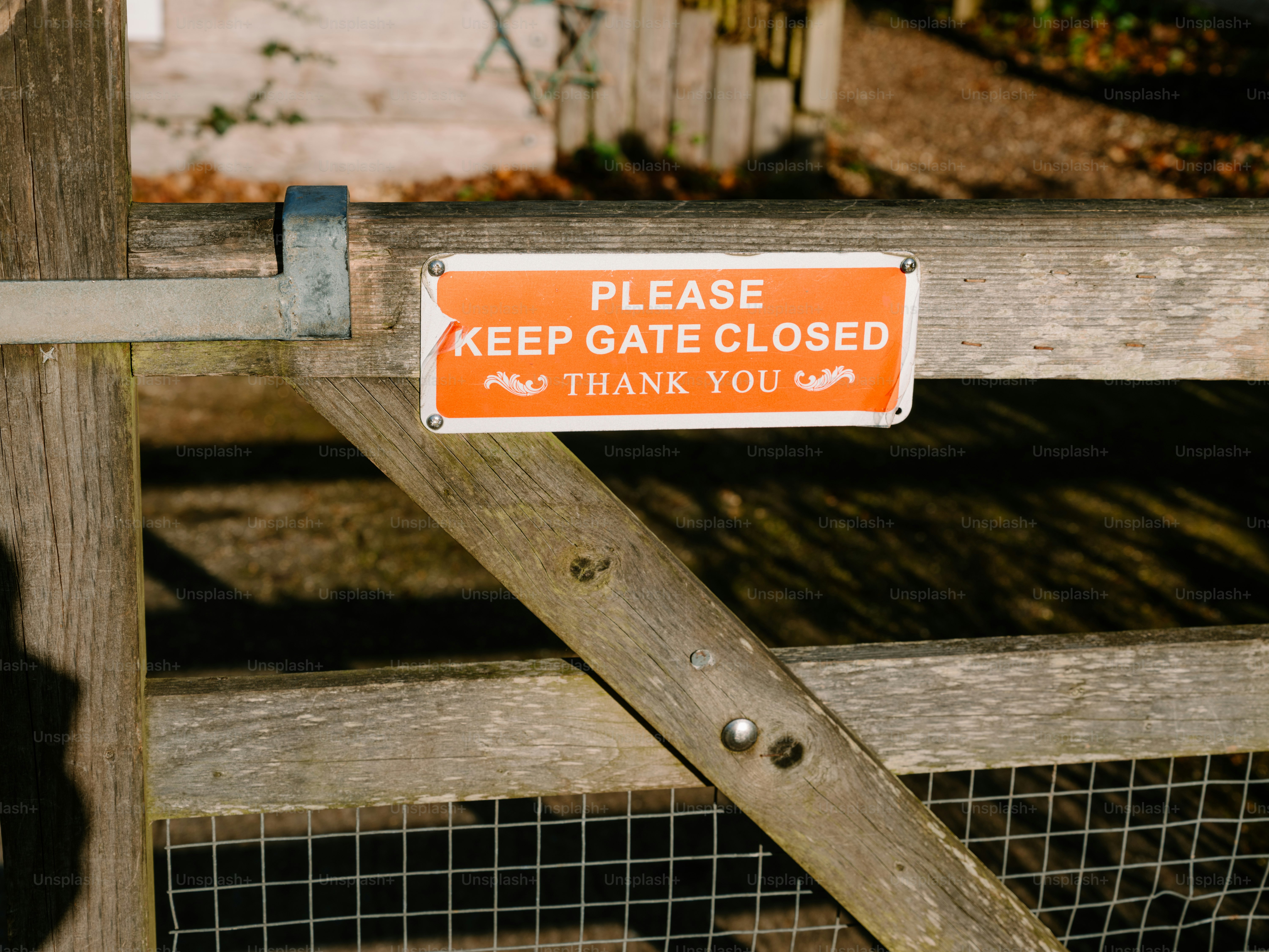 Orange sign on wooden gate says keep closed