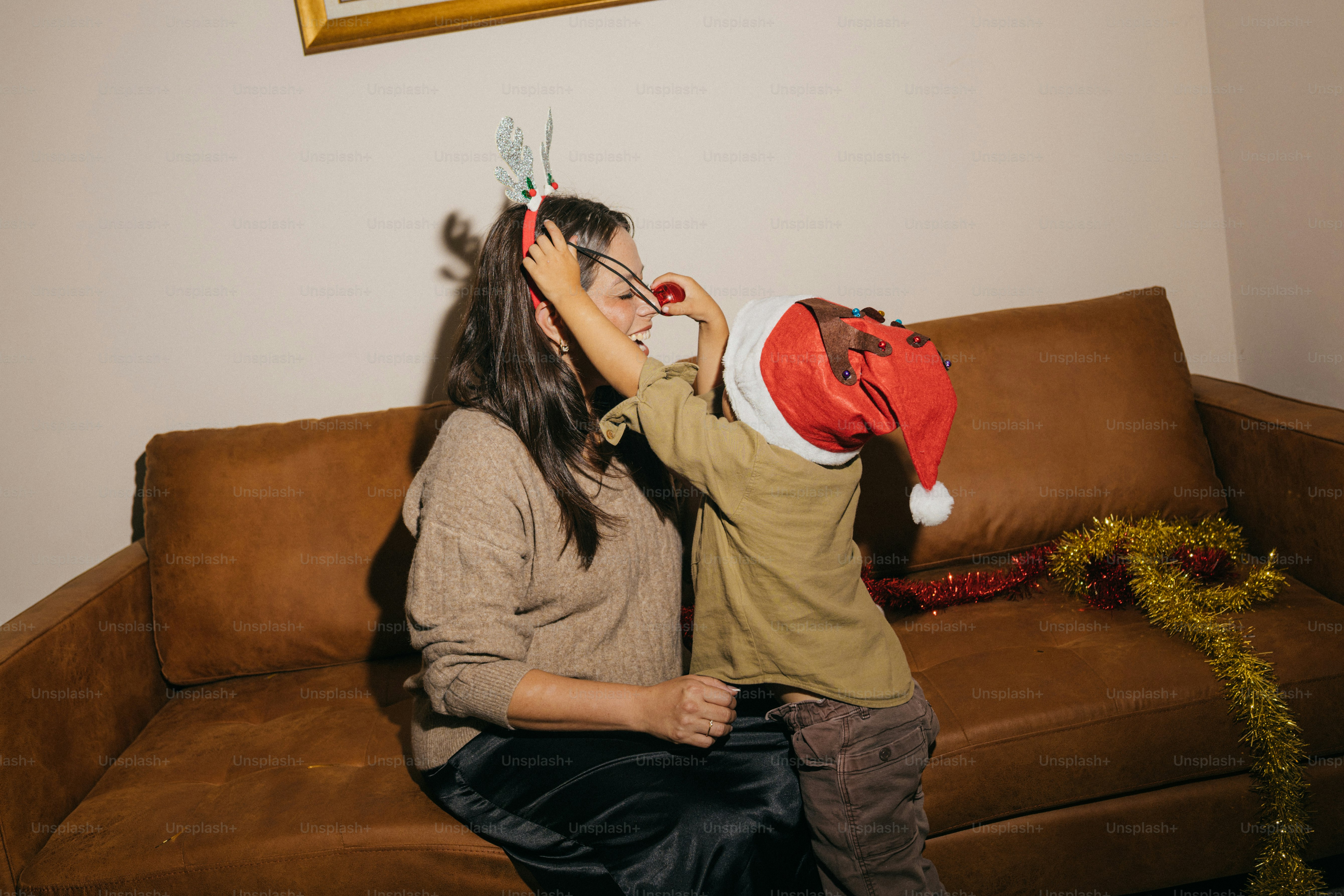 Mutter und Kind feiern Weihnachten auf einer Couch.