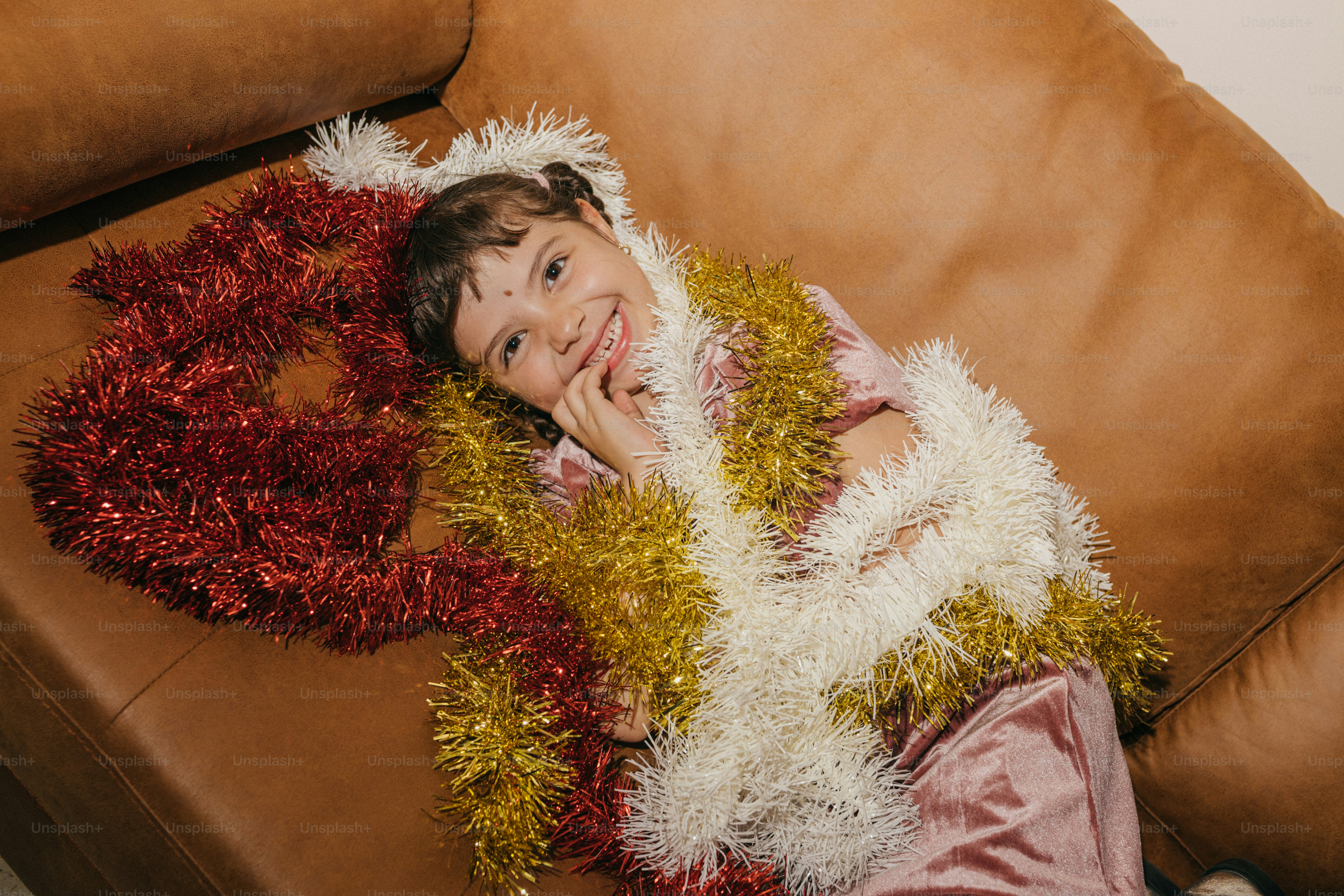 Ein lächelndes Kind liegt auf einer Couch, bedeckt mit Lametta.