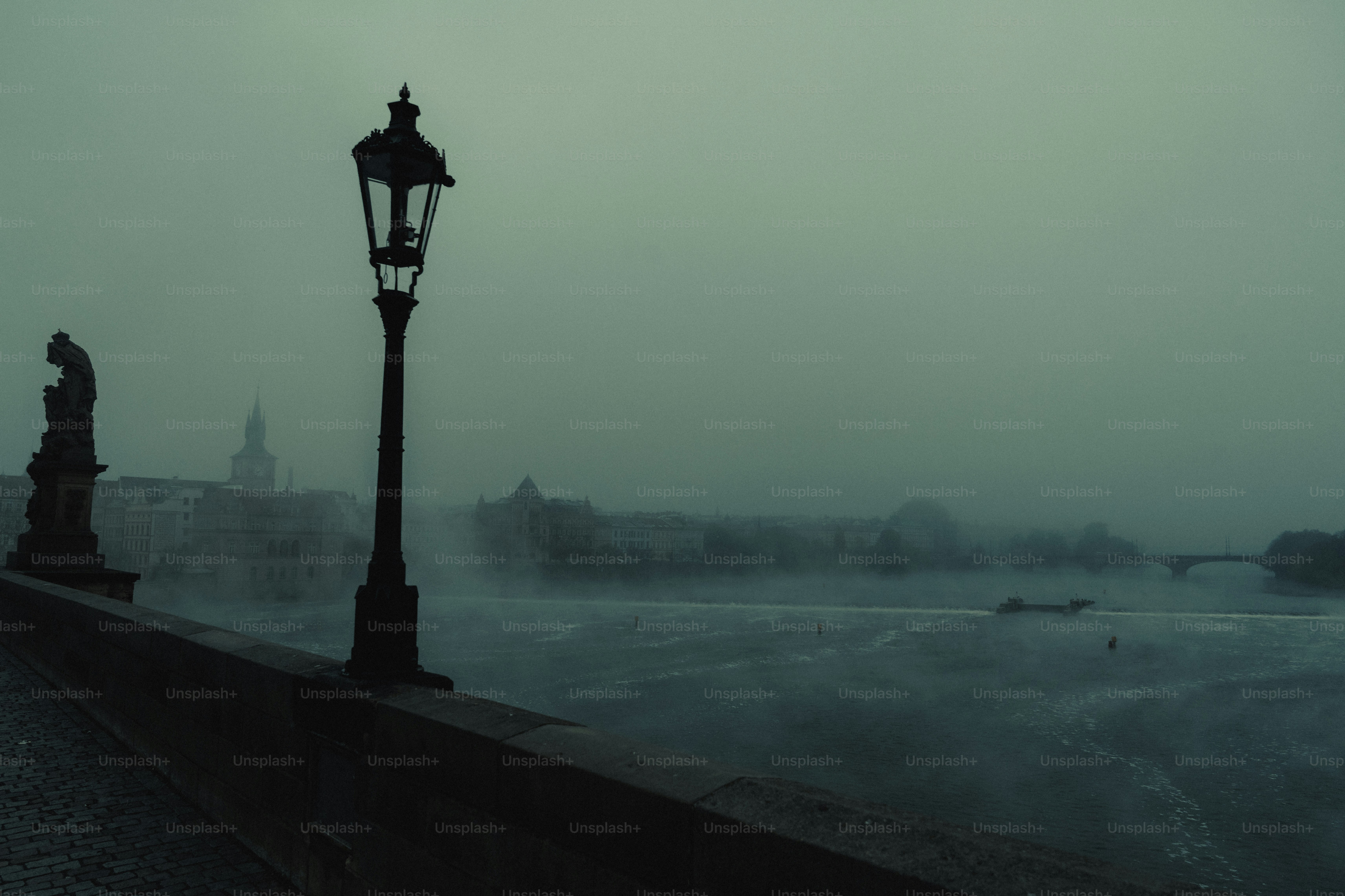 Foggy city skyline with a lamppost and statue.