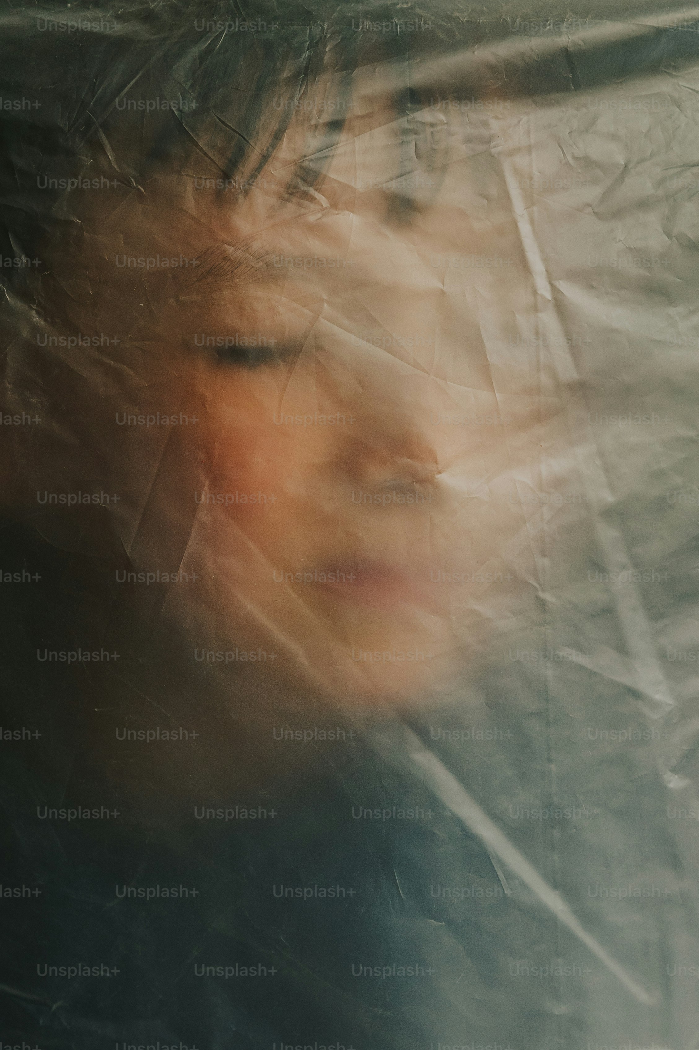 Das Gesicht eines Kindes, verdeckt von zerknitterter Plastikfolie.