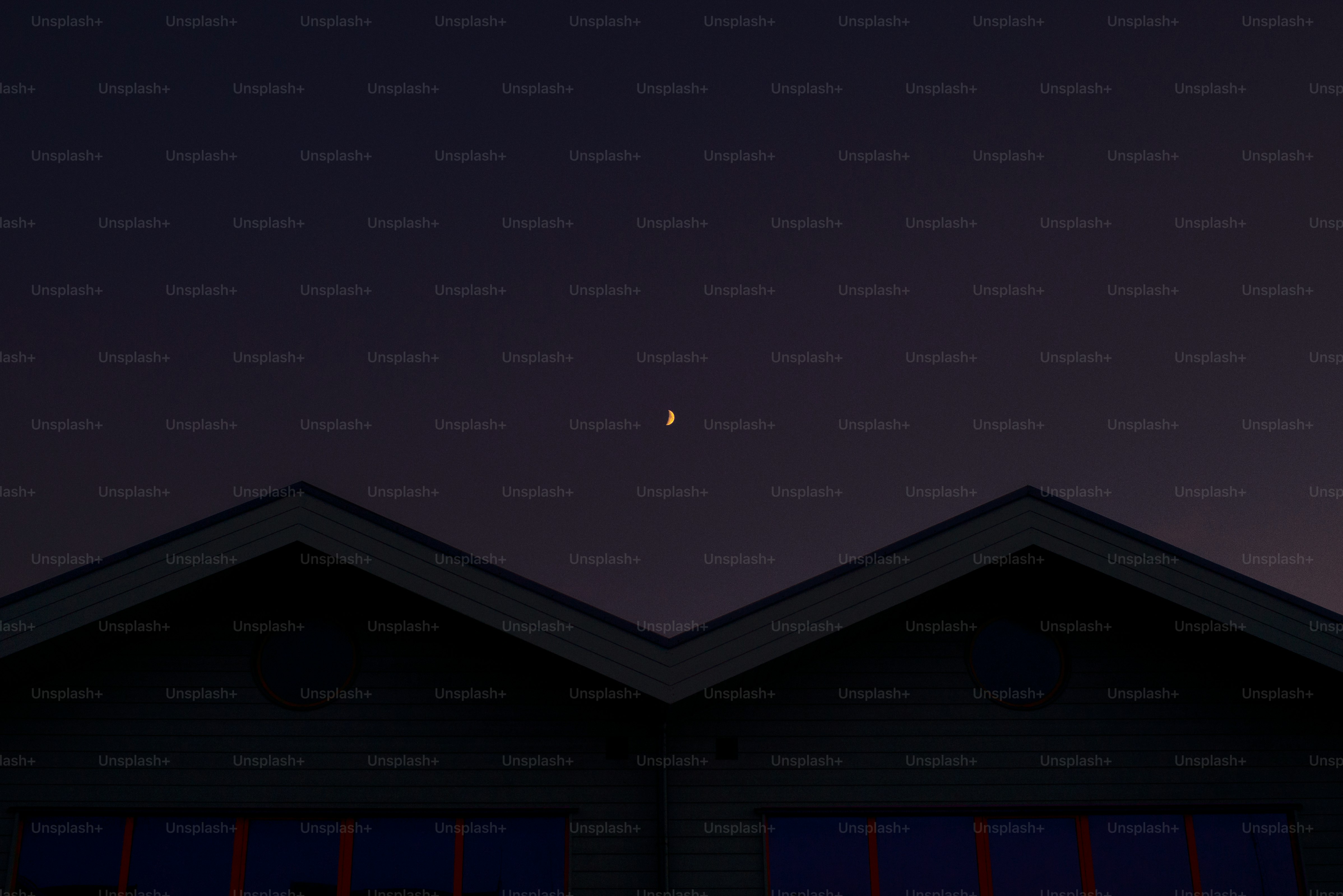 Crescent moon visible above rooftops at dusk
