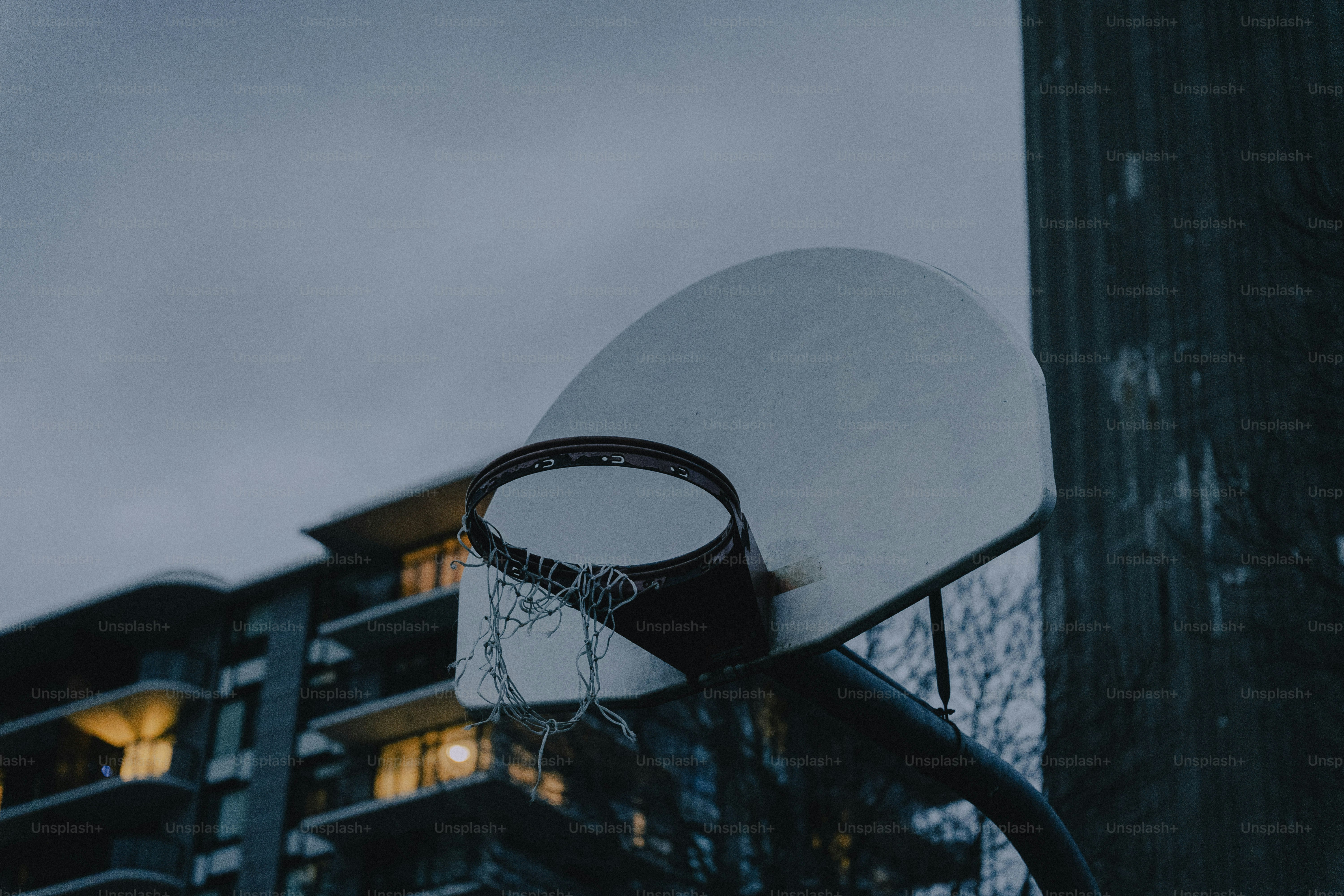 흐린 하늘과 건물을 배경으로 농구 골대를 치는 모습.